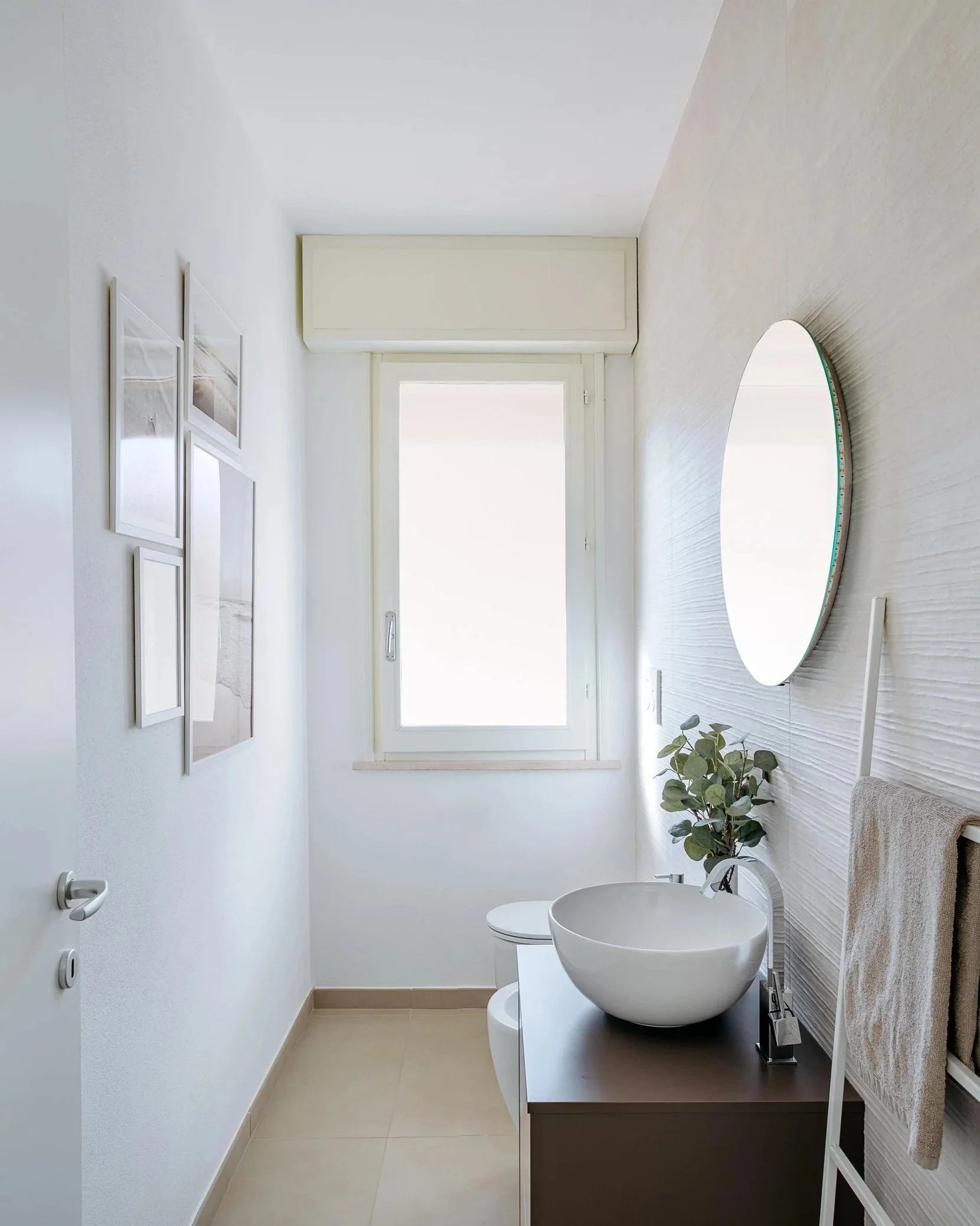 Bagno con lavabo moderno e specchio rotondo, luminoso e minimal.