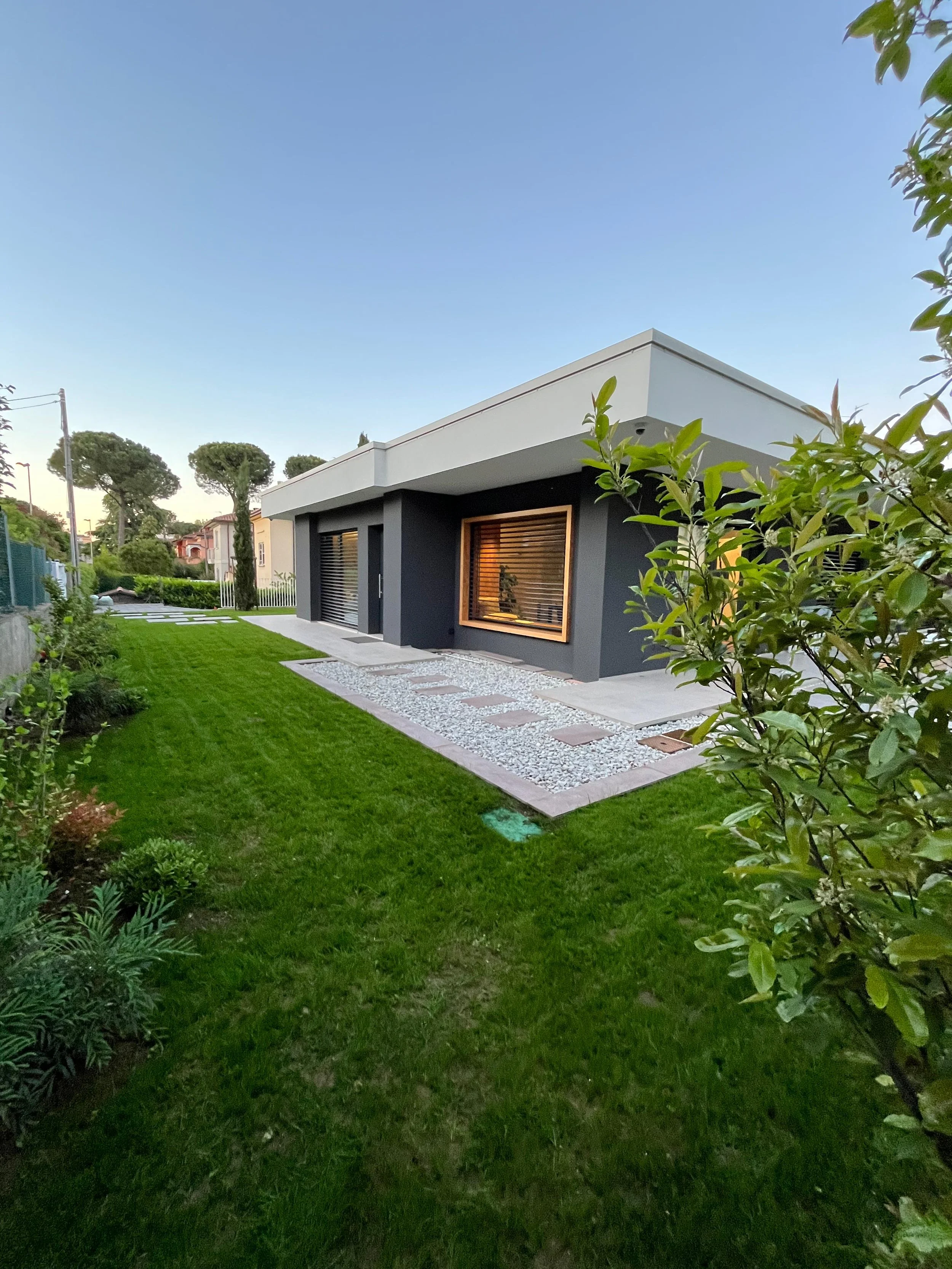 Vista frontale di villa moderna con ampio giardino e linee architettoniche essenziali. Progetto residenziale curato da DAT Architetti.