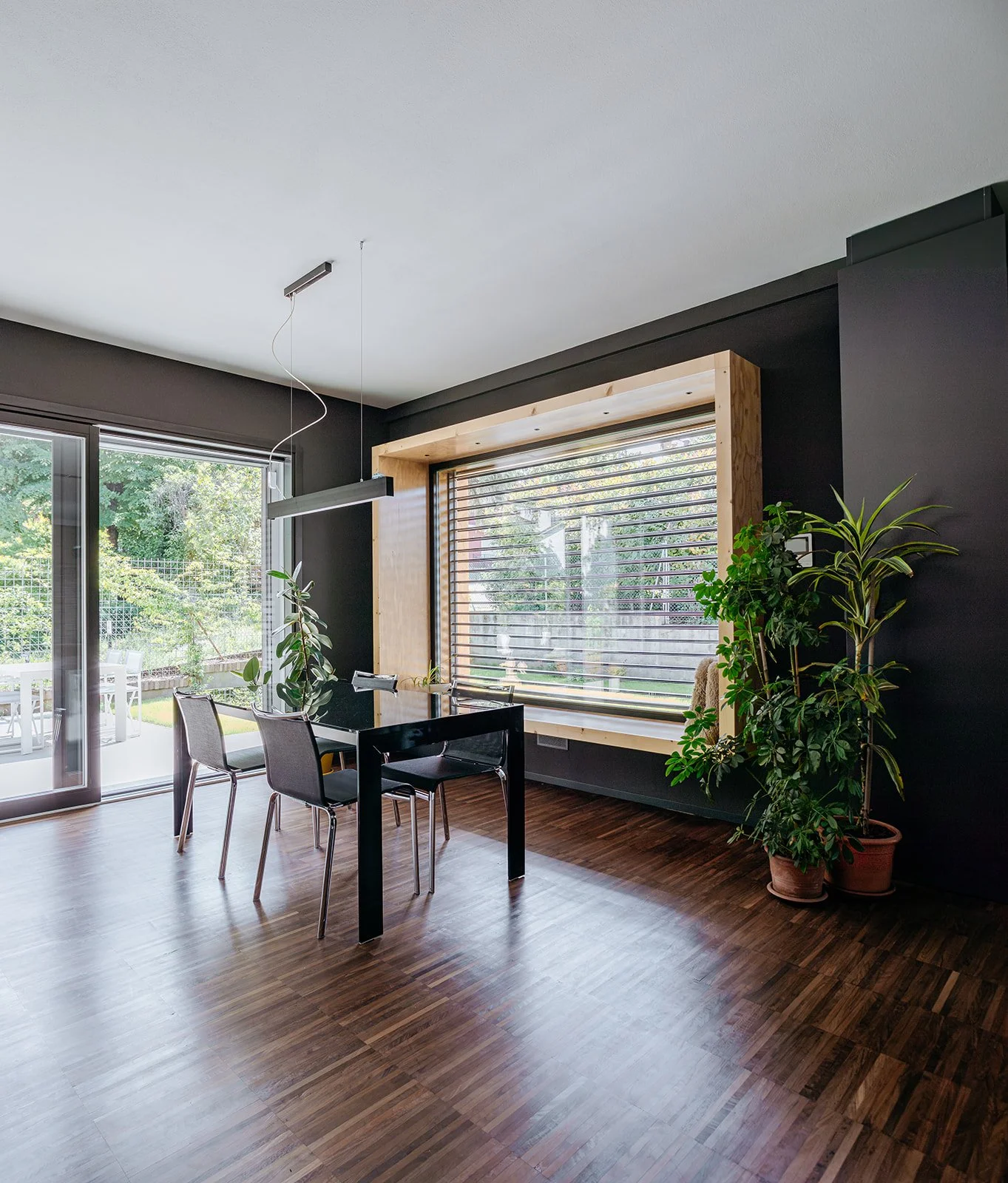 Zona pranzo con ampia vetrata sul giardino, pavimenti in legno e arredi contemporanei. Casa a Savignano progettata da DAT Architetti.