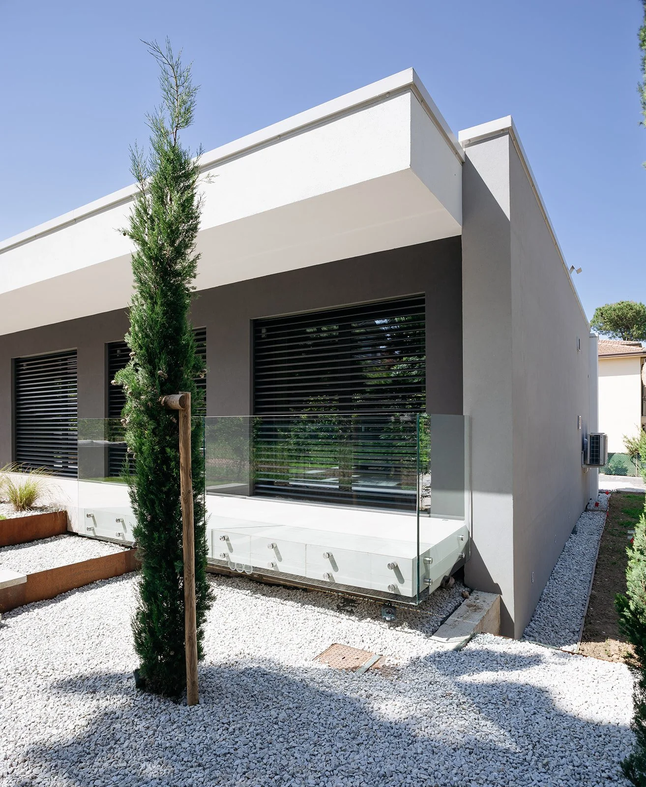 Facciata di villa dal design contemporaneo con ampie vetrate e dettagli in pietra, Savignano – DAT Architetti.
