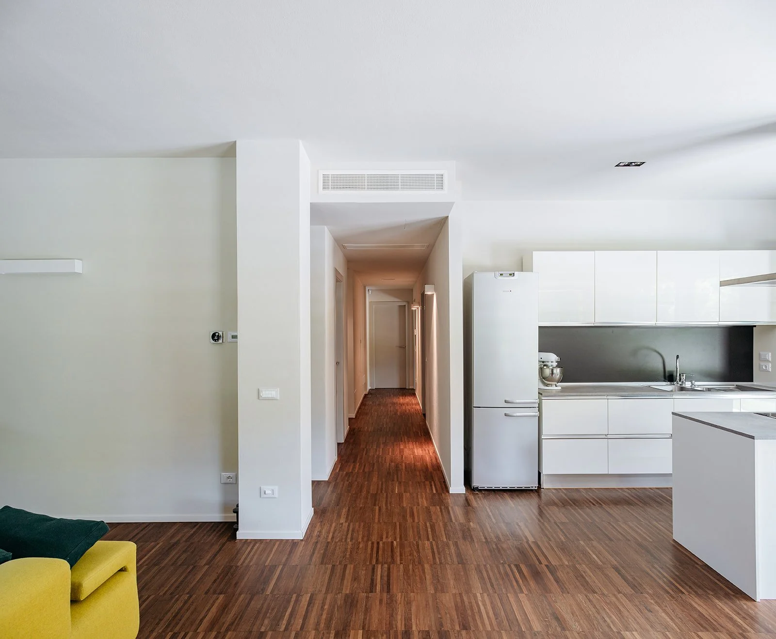 Vista prospettica del corridoio e della cucina di Casa a Savignano. Spazi fluidi, luce naturale e materiali caldi in un progetto firmato DAT Architetti.
