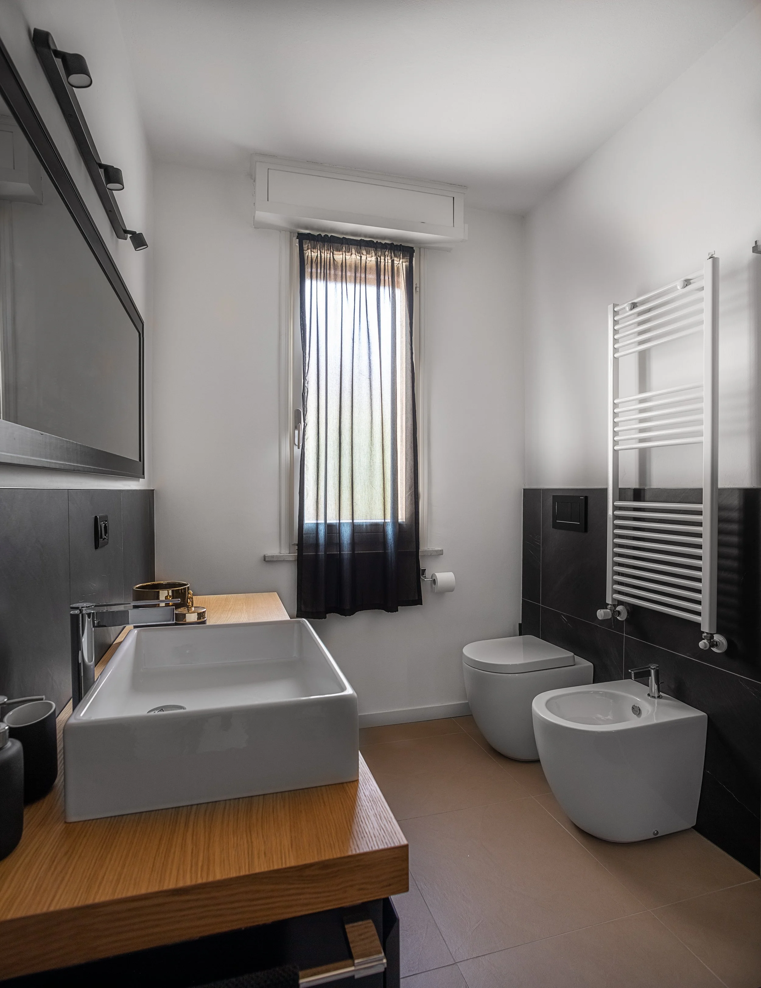 Bagno moderno con sanitari sospesi e rivestimenti nero, progetto residenziale di DAT Architetti.