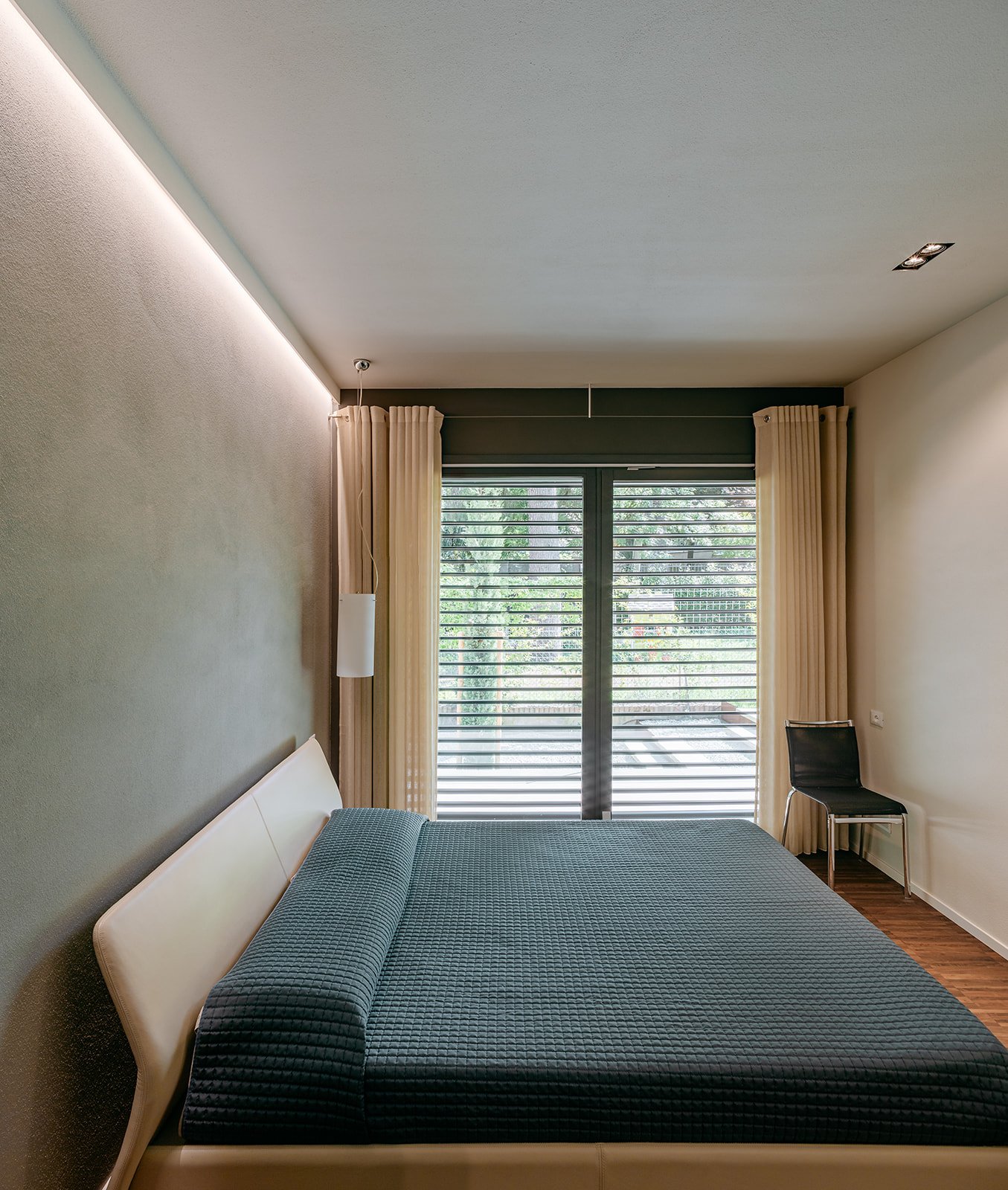 Camera matrimoniale elegante con pareti neutre e grandi aperture vetrate, parte del progetto Casa a Savignano di DAT Architetti.