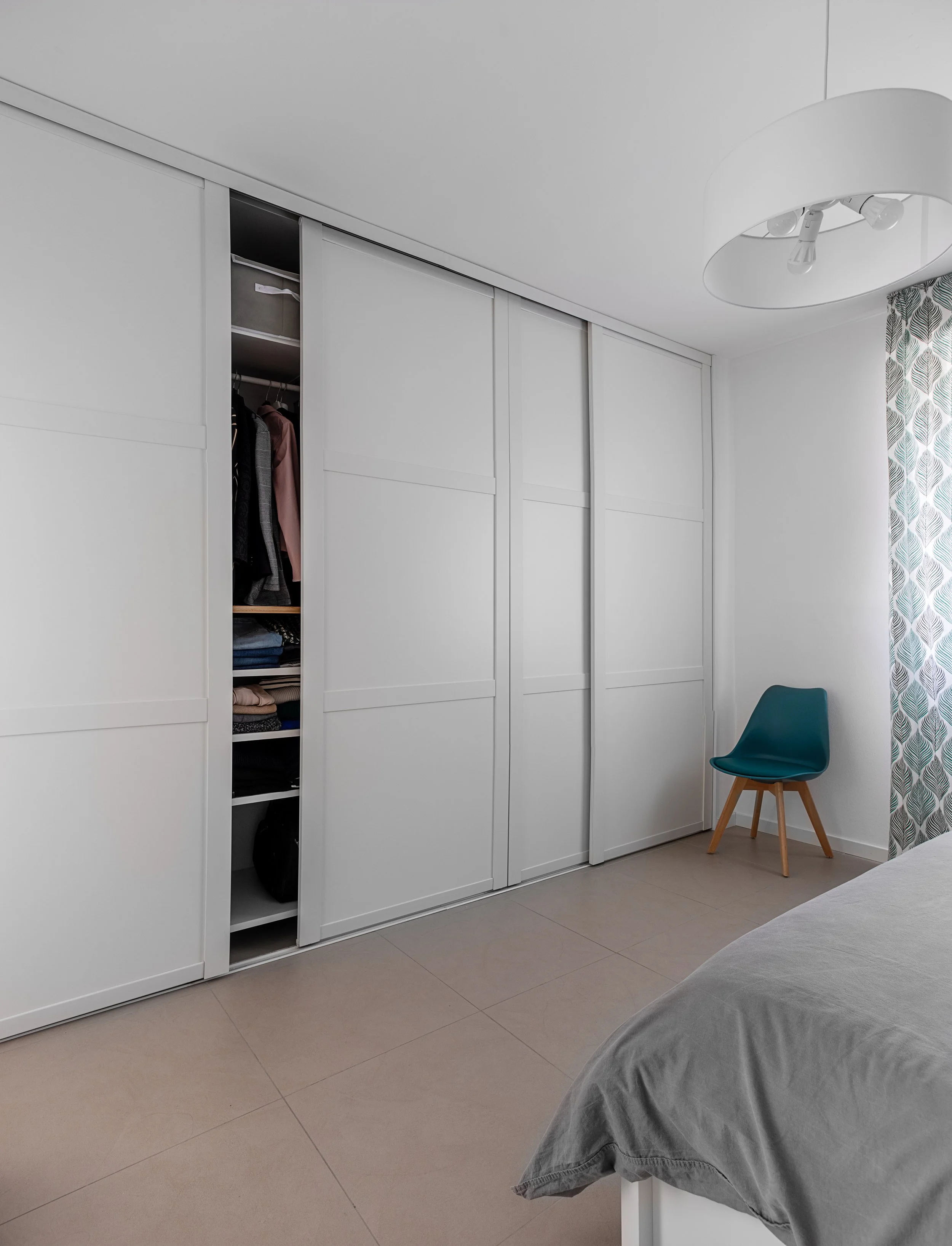 Cabina armadio con ante scorrevoli bianche in camera da letto, progetto funzionale di DAT Architetti.