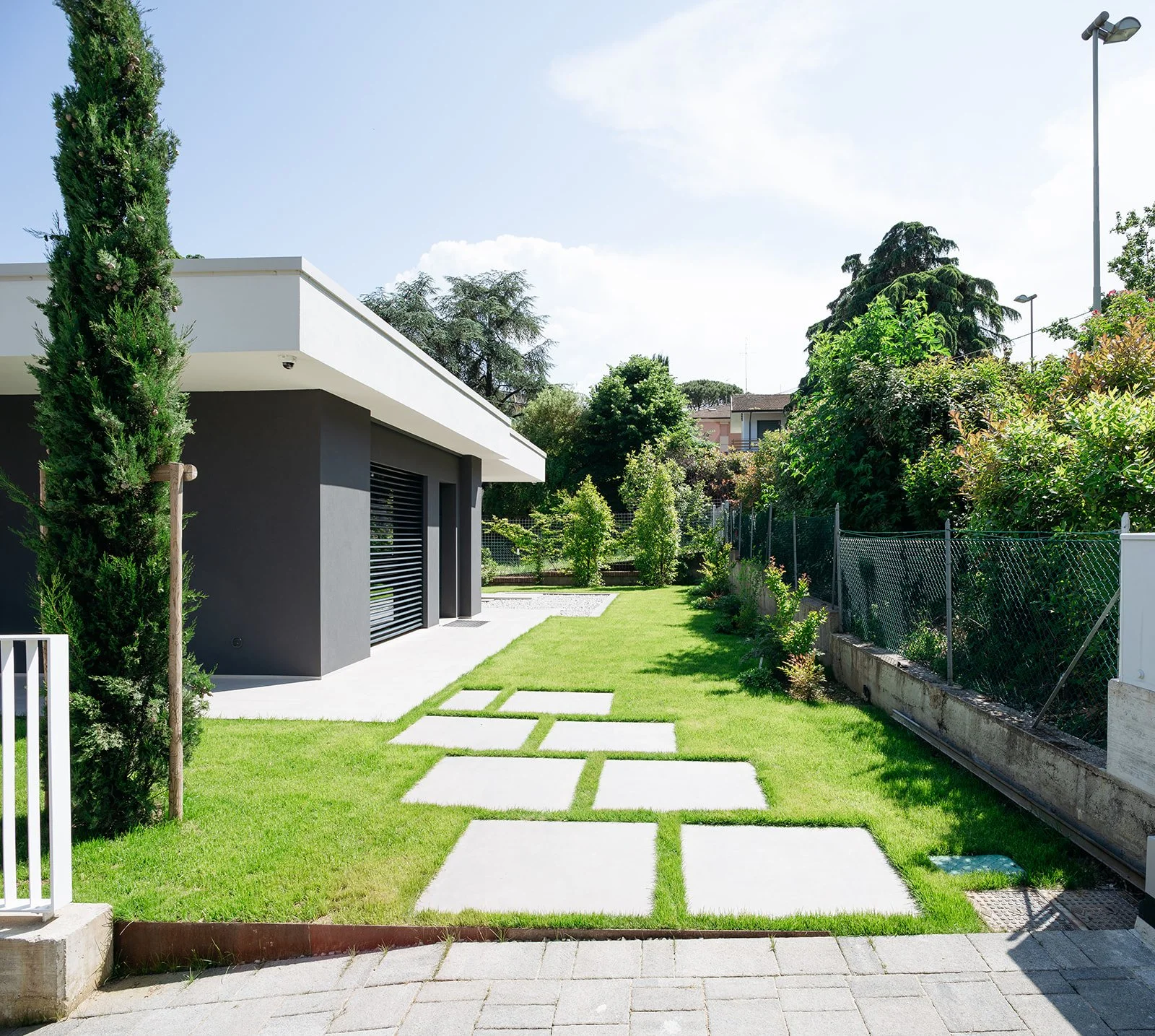 Villa moderna con giardino verde e percorso in pietra geometrico, progettata da DAT Architetti.
