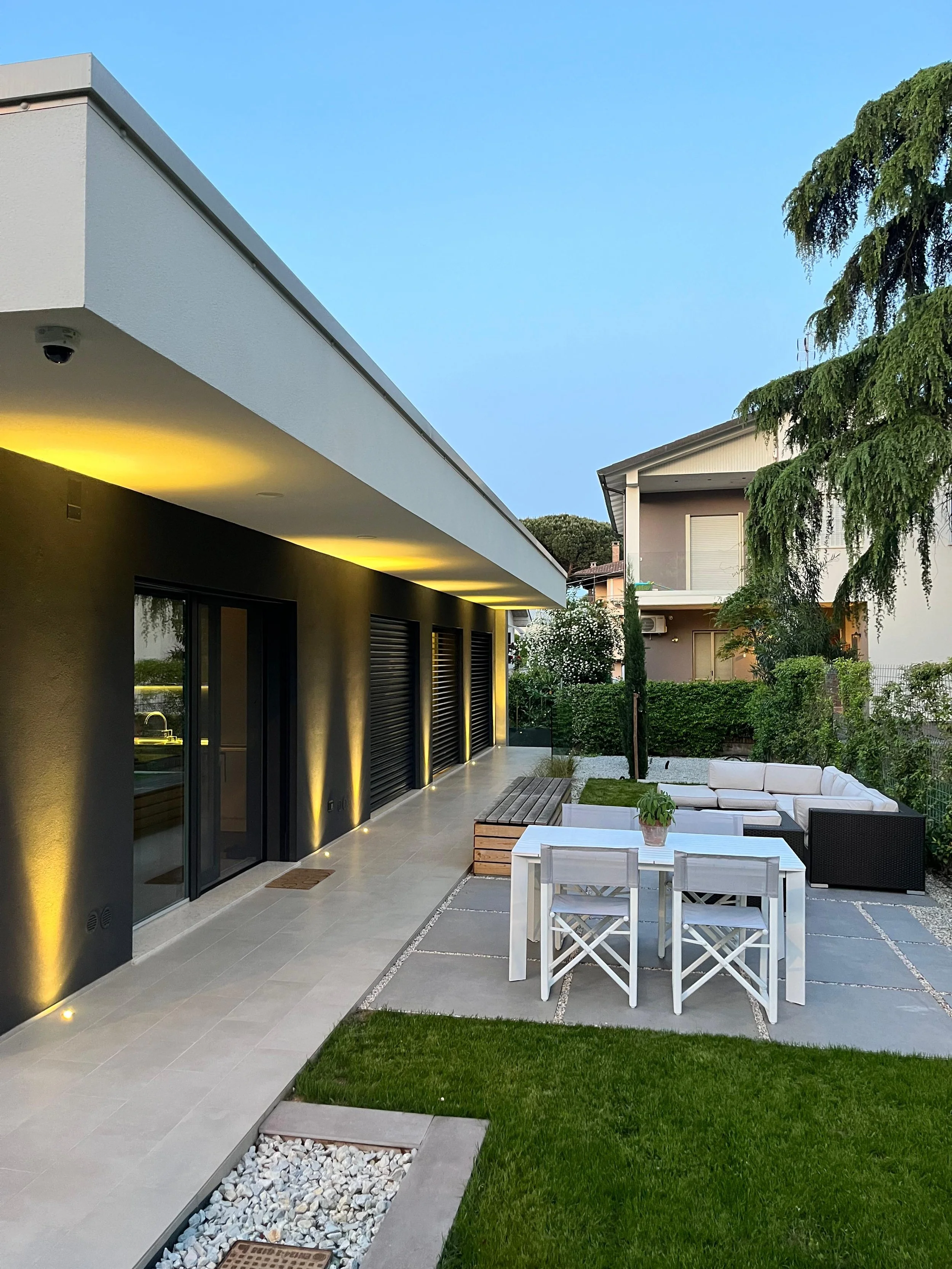 Esterno serale di una villa contemporanea illuminata, progettata da DAT Architetti a Savignano. Atmosfera elegante e materiali di pregio.