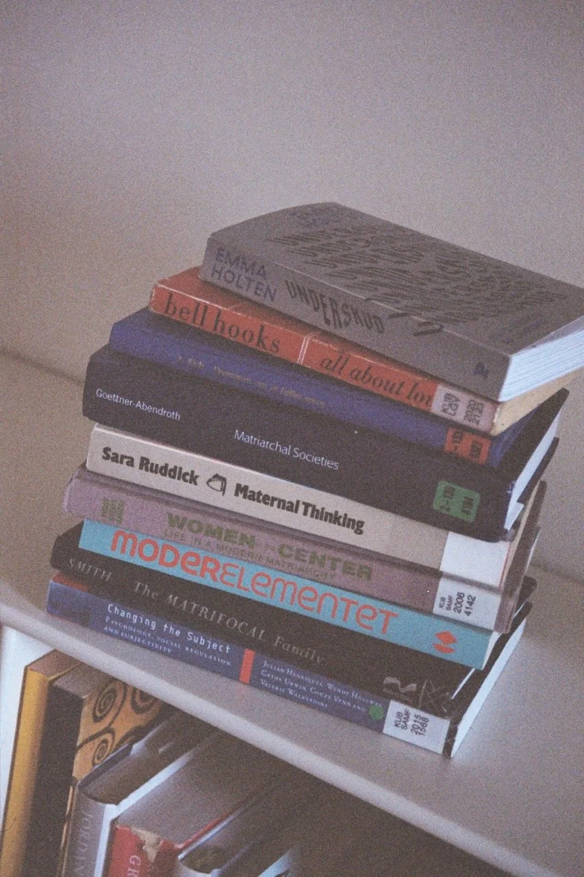 A stack of academic books on a white surface, including titles on gender, matriarchal societies, maternal thinking, women, modern movements, and social change.