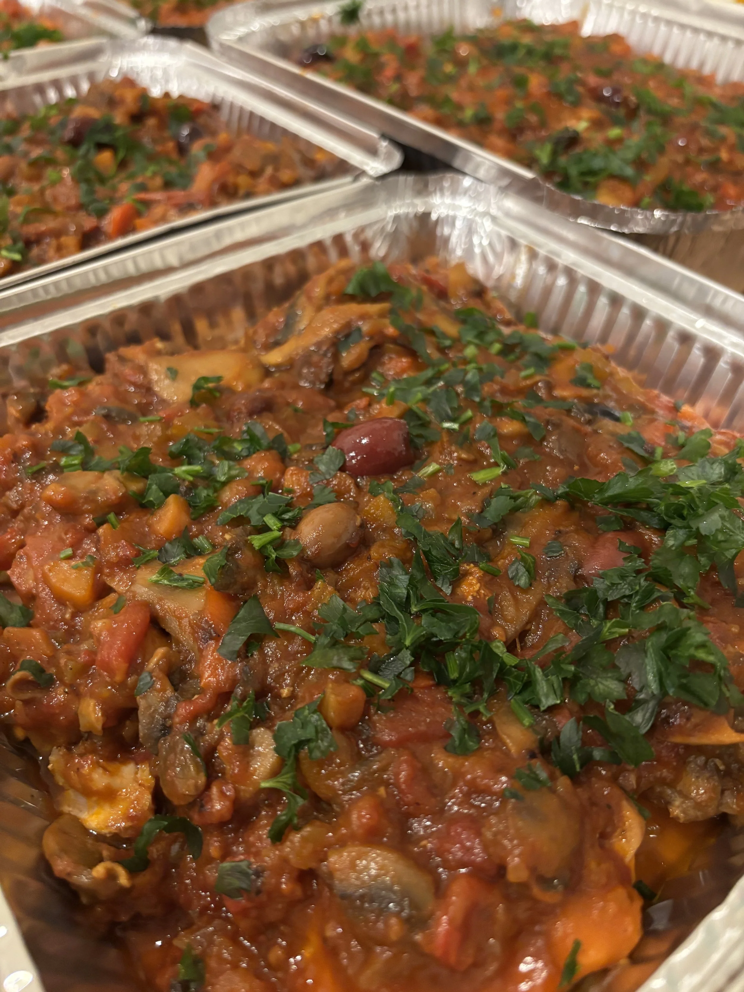 Tray of cooked vegetable chili garnished with chopped parsley.