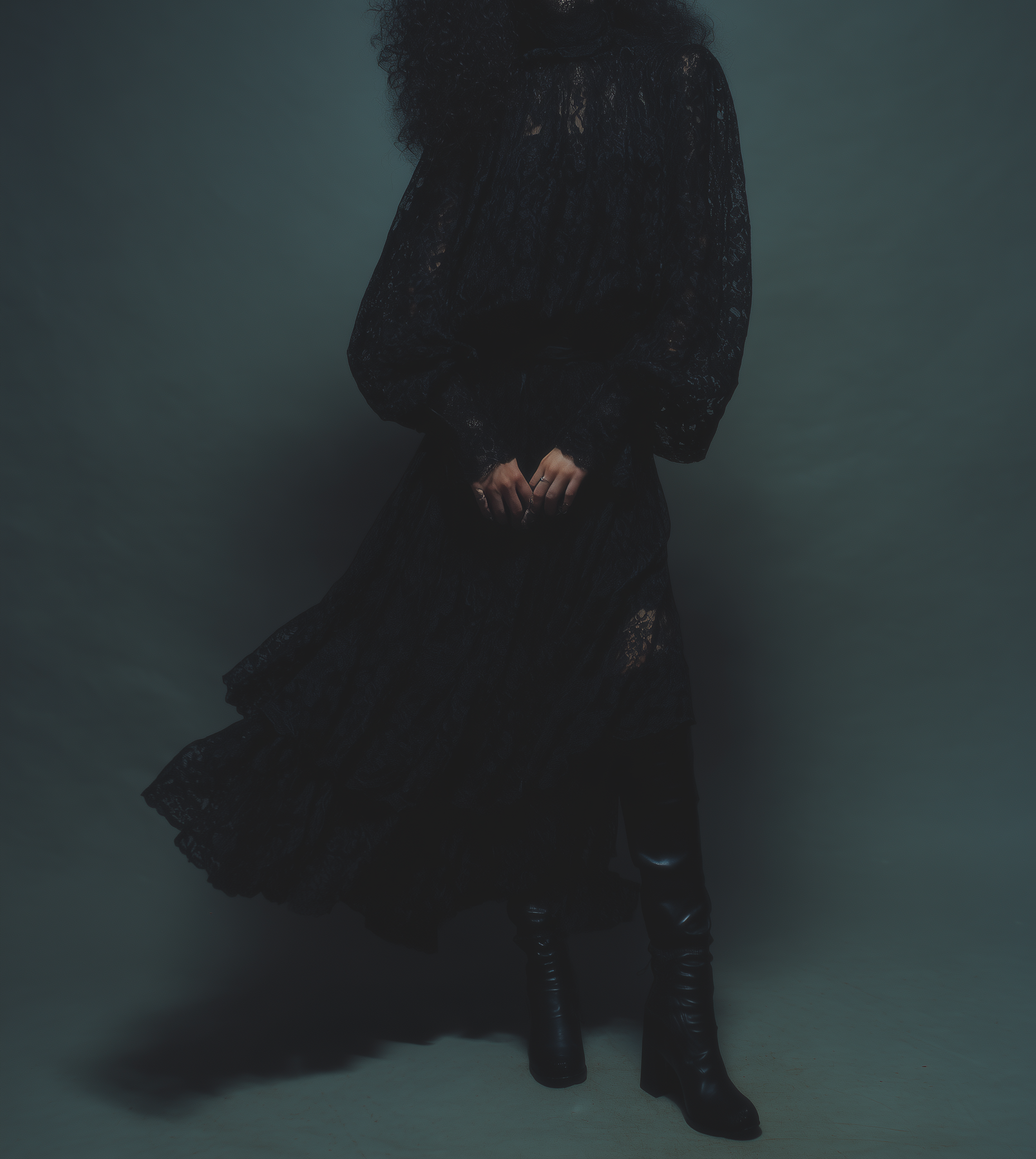 Frau trägt ein langes schwarzes Kleid vor grauem Hintergrund