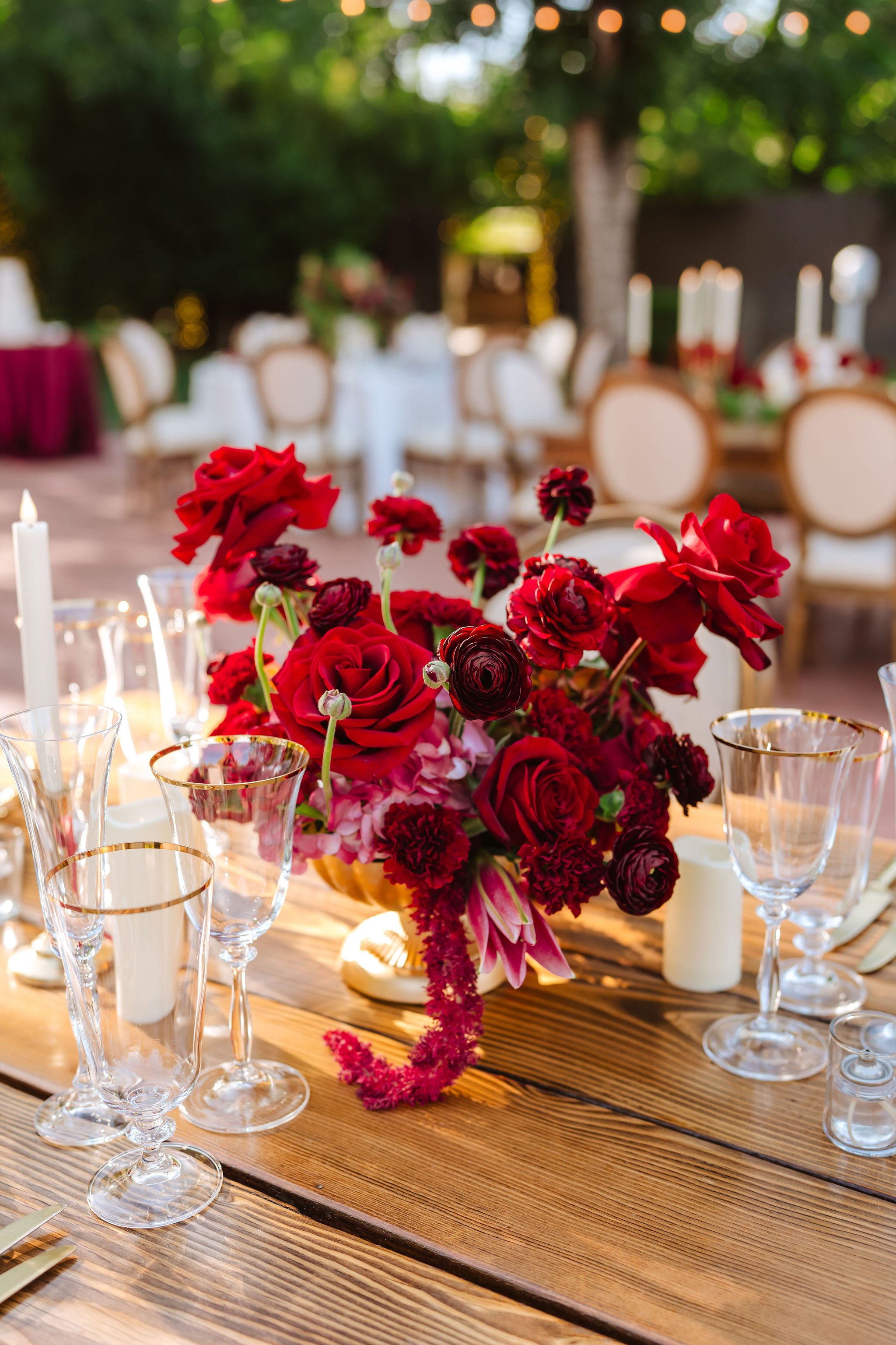Dramatic red wedding centerpiece with roses and rich burgundy flowers on an elegant reception table.