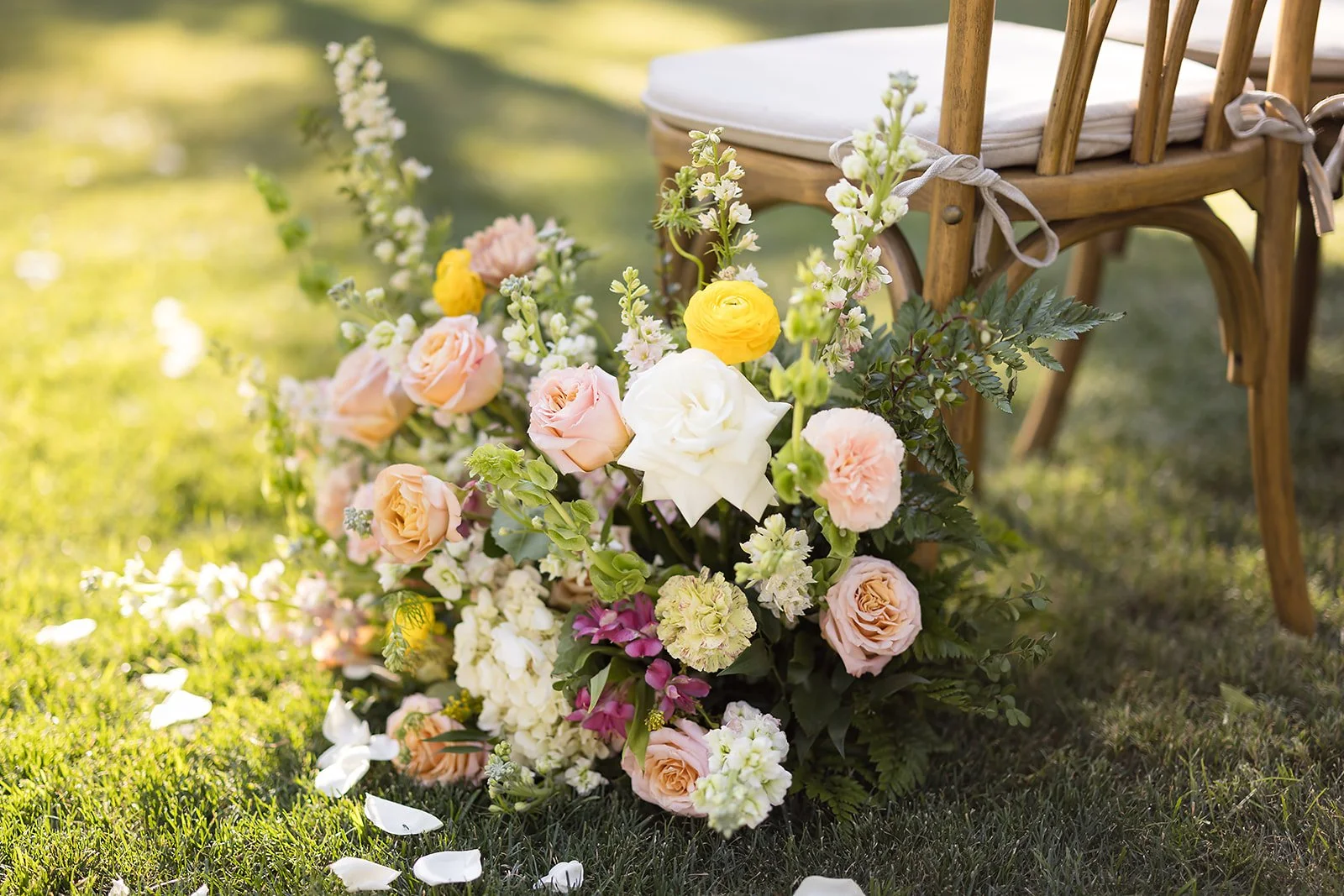 Romantic wedding aisle arrangement with peach roses, white flowers, yellow blooms and soft greenery at Venue at the Grove.