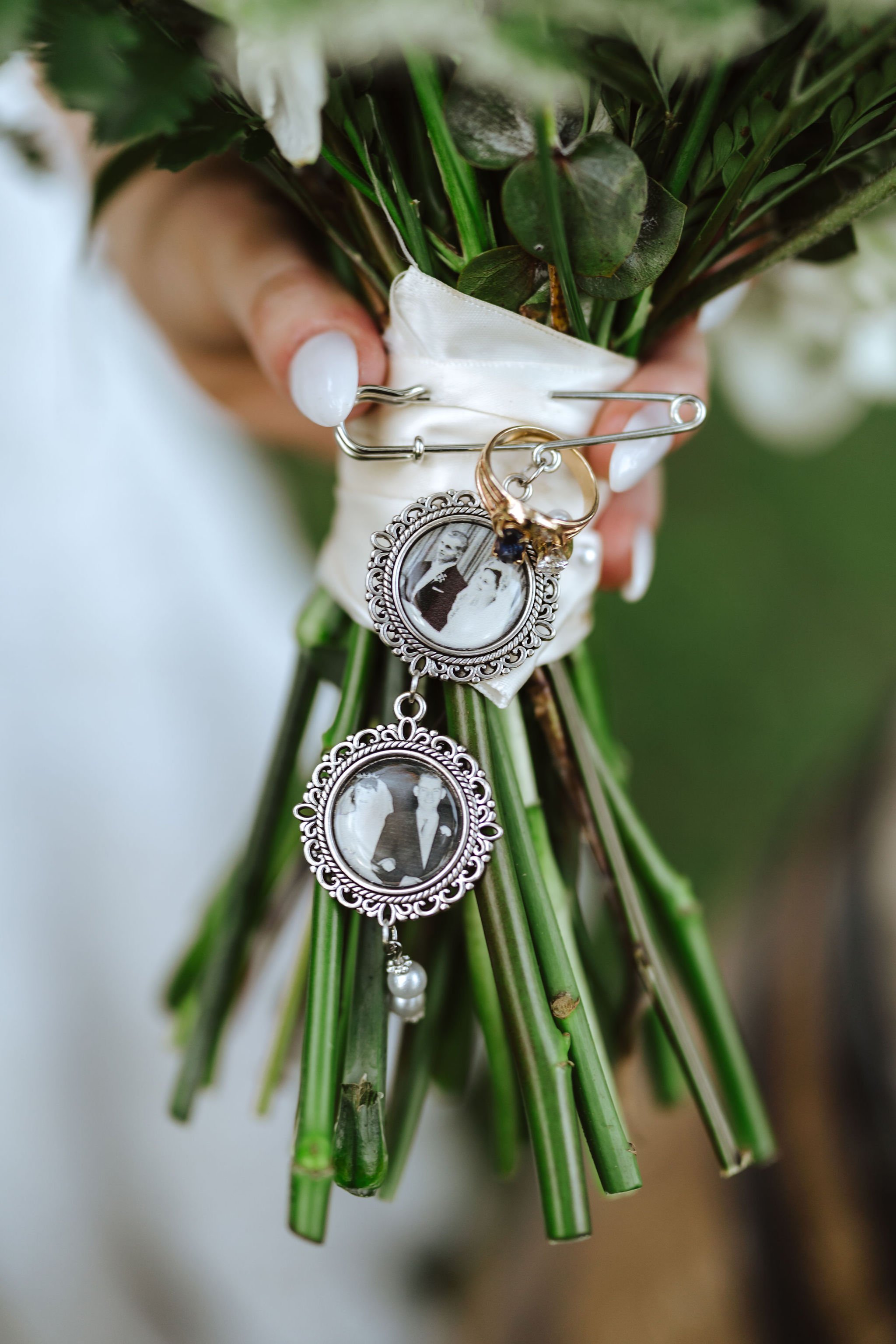 Close-up of sentimental charms tied to the stems of a white and green bridal bouquet.