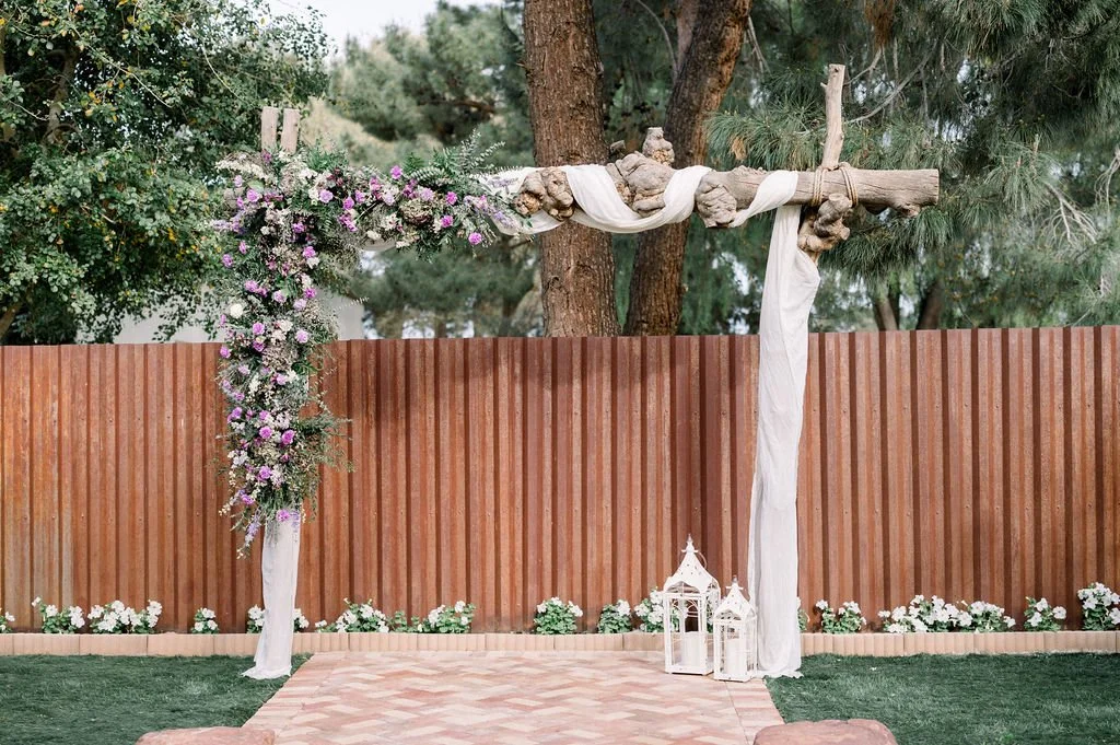 Rustic wedding ceremony backdrop decorated with lavender, blush and white floral installations and soft greenery.