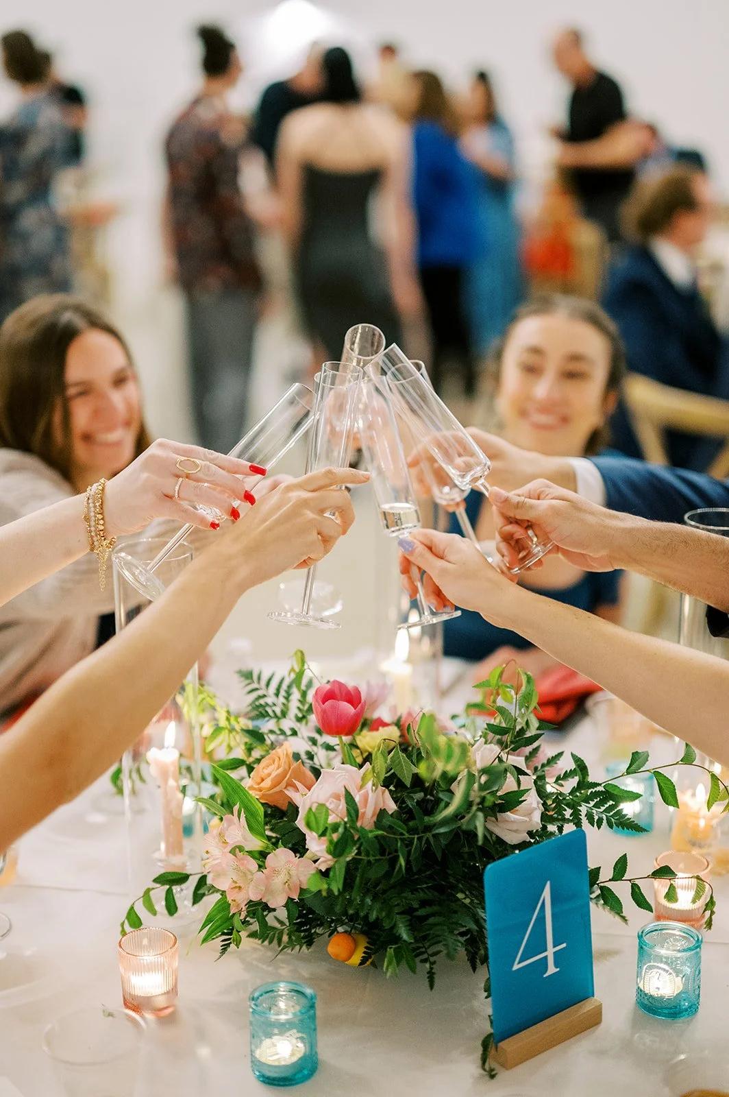Wedding guests celebrating around colorful reception flowers and playful table décor.