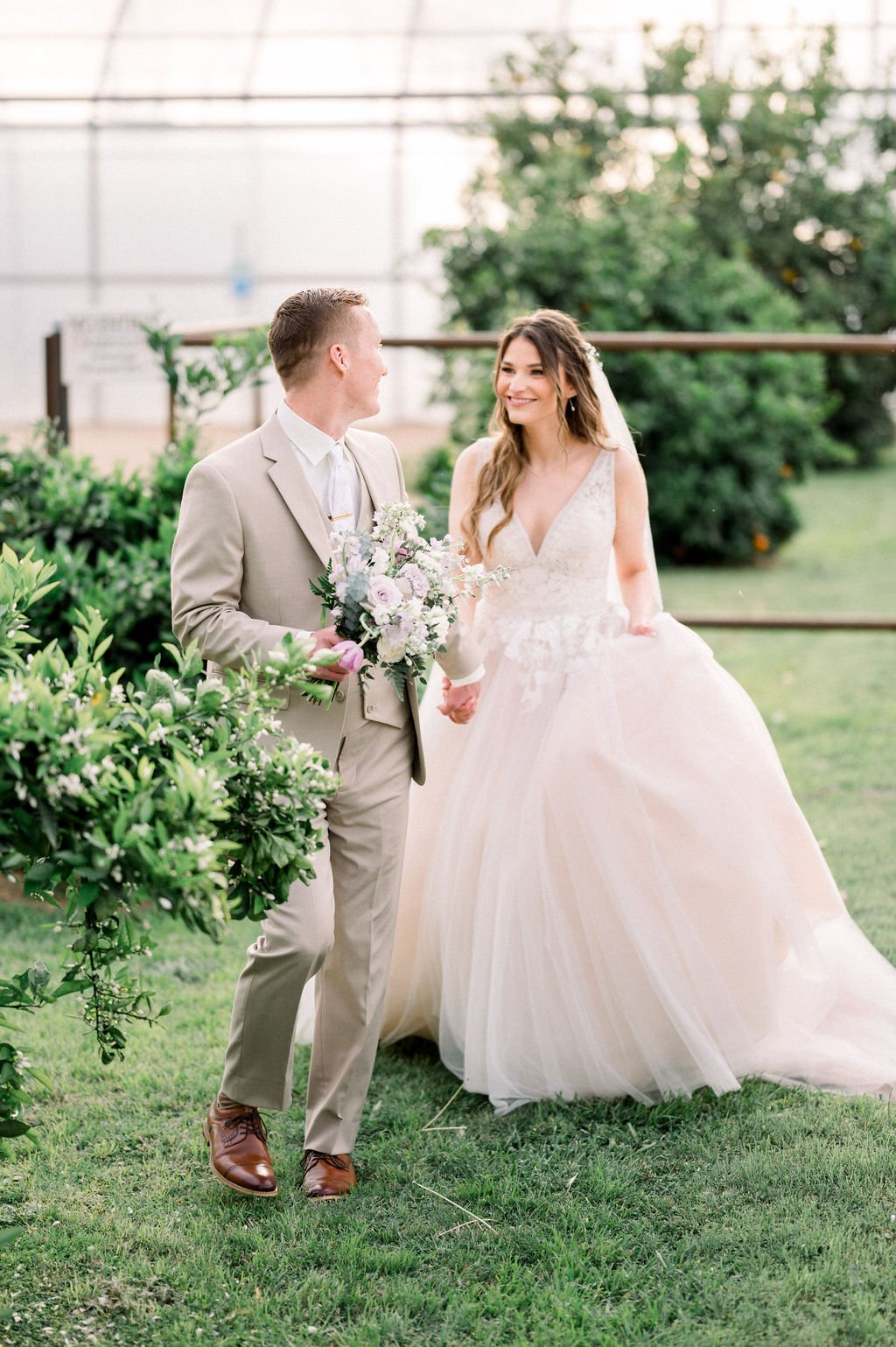 Bride and groom portrait surrounded by greenery with a soft lavender, blush and white garden-style bouquet.
