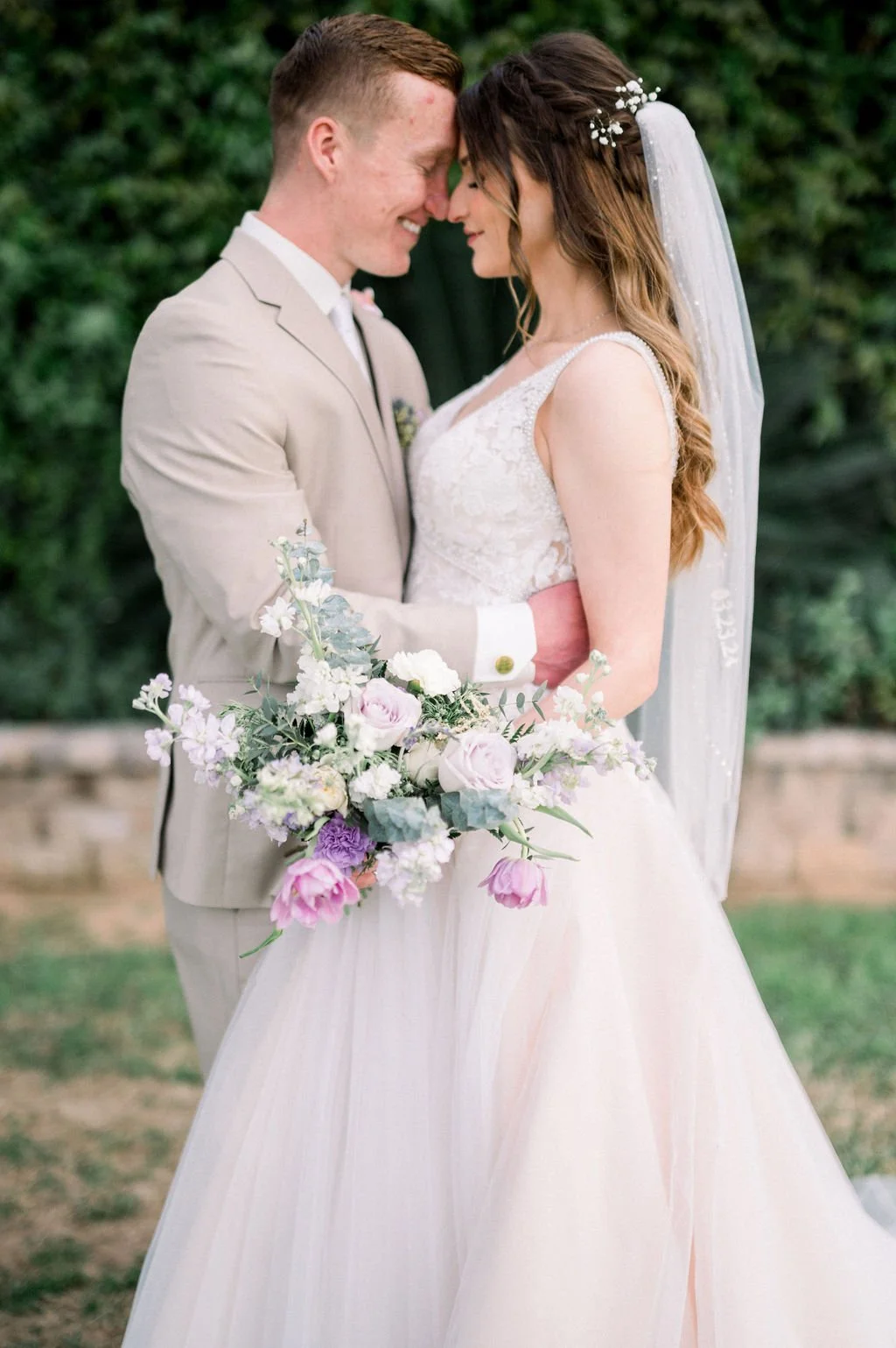 Bride and groom holding a romantic lavender and blush wedding bouquet at their Knotty Barn wedding.