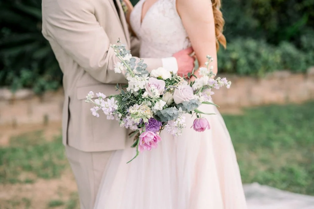 Close-up of a whimsical bridal bouquet with lavender, blush pink and white flowers accented with eucalyptus and greenery.