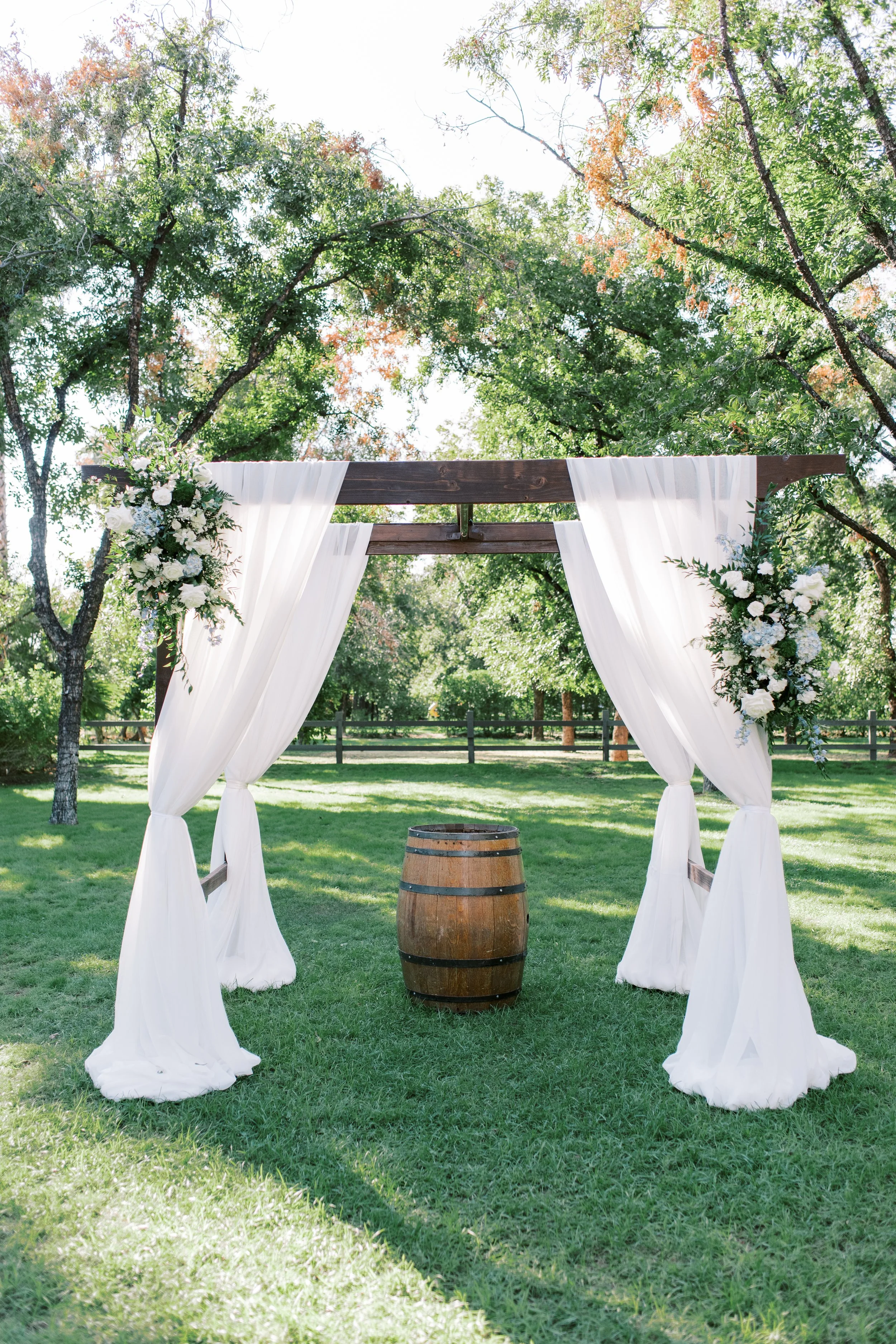 Outdoor wedding ceremony arch with flowing white draping and greenery at Venue at the Grove in Phoenix.