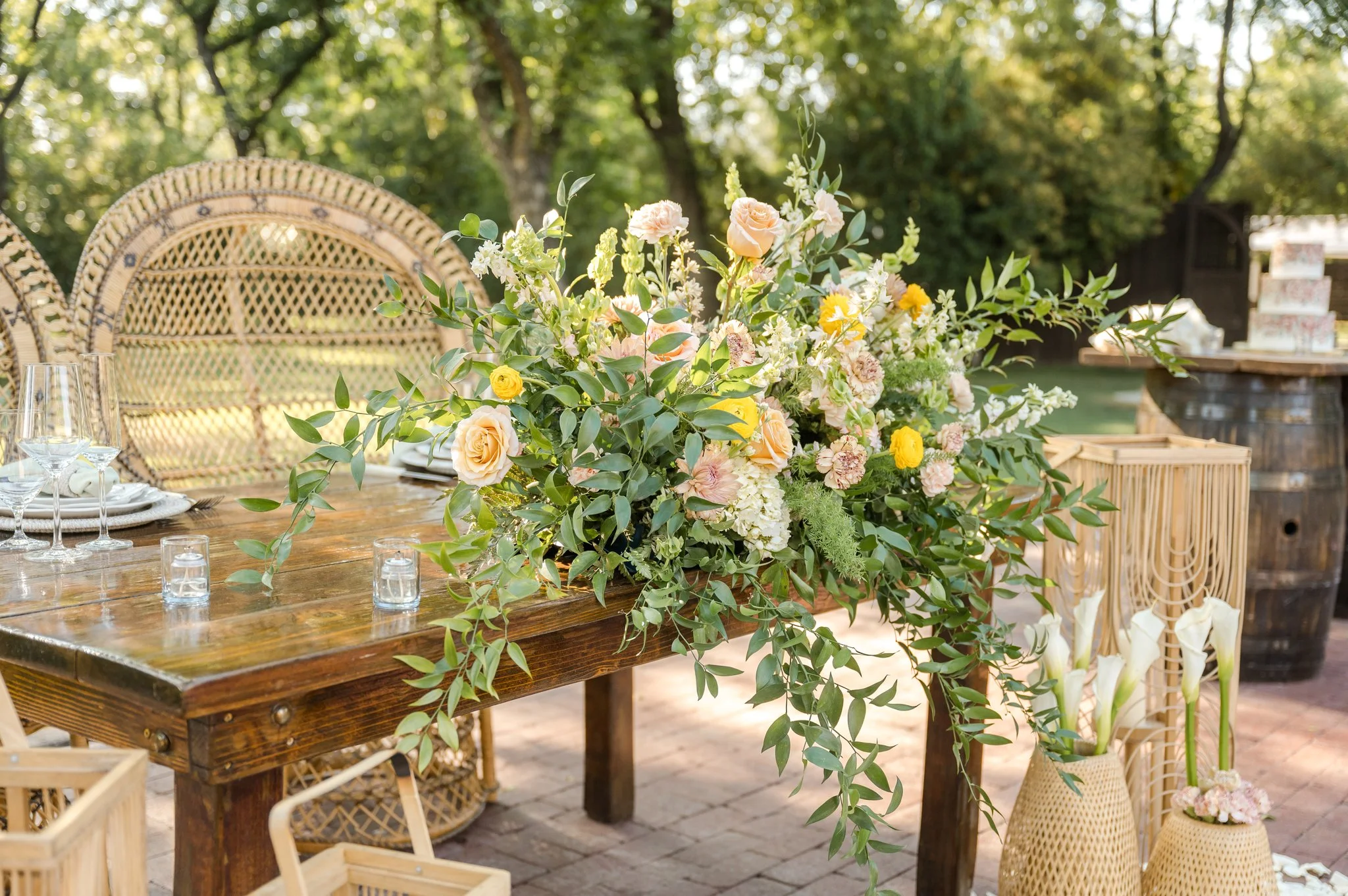 Colorful garden wedding centerpiece with peach, yellow, pink and lavender flowers arranged organically with greenery.
