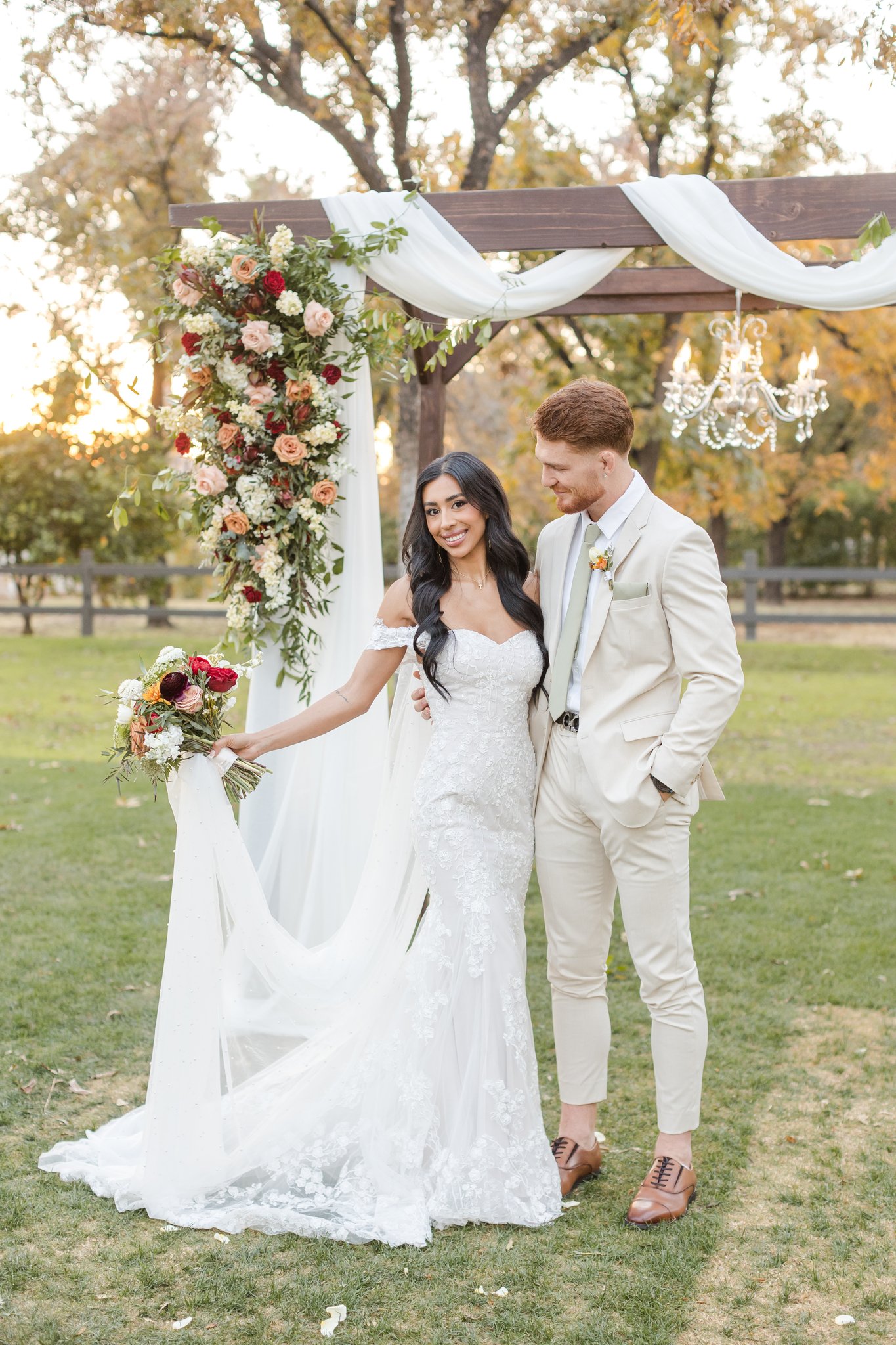 Bride and groom beneath a romantic fall floral ceremony arch at Venue at the Grove in Phoenix.