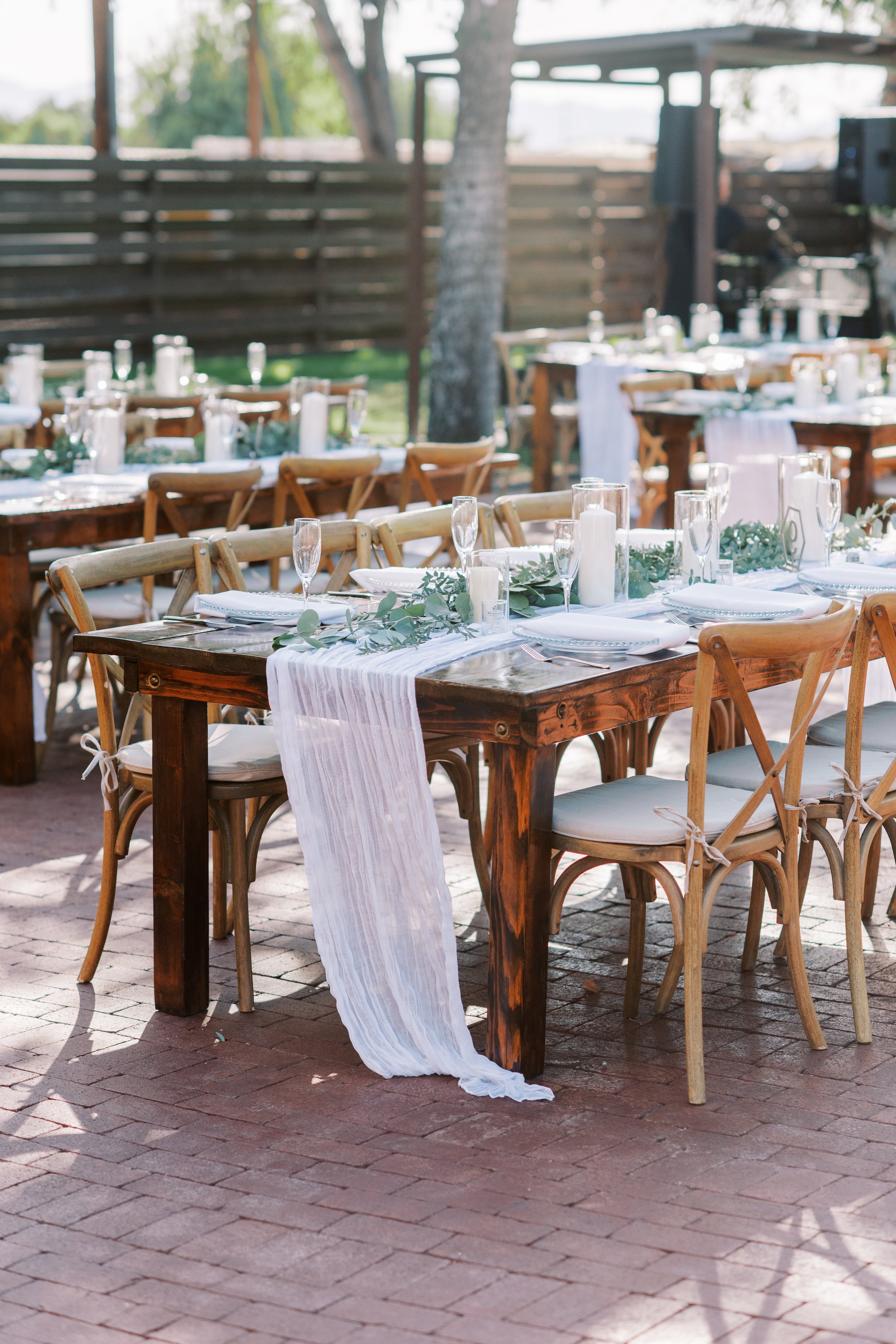 Garden wedding reception with long wooden tables, soft blue linens and elegant white floral details.