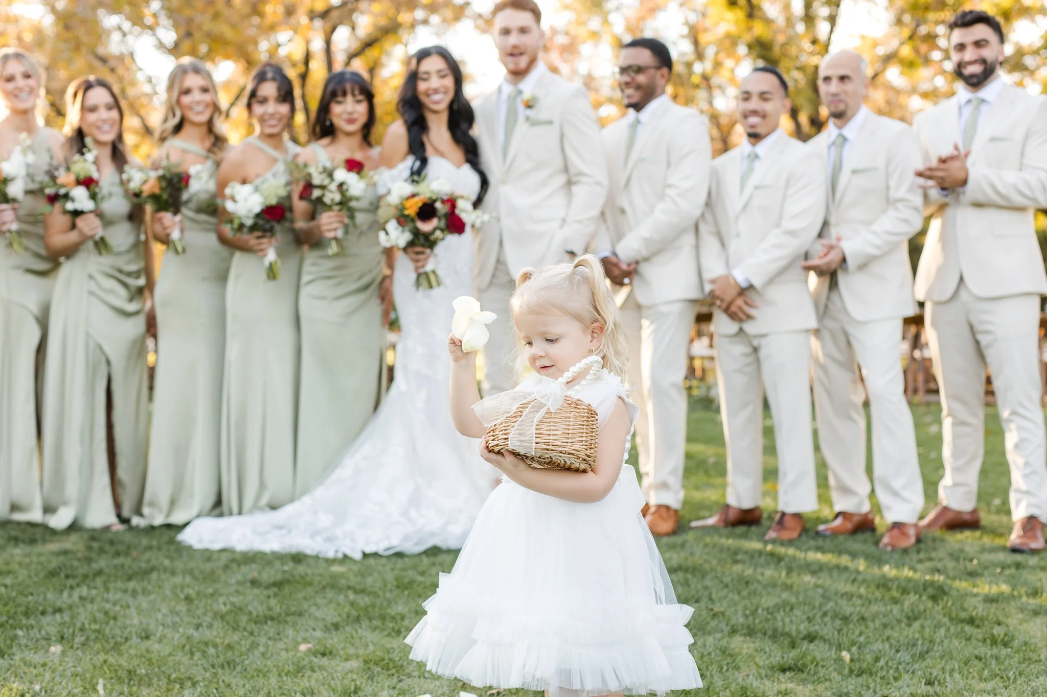Wedding party celebrating outdoors with sage dresses and warm fall floral bouquets at Venue at the Grove.