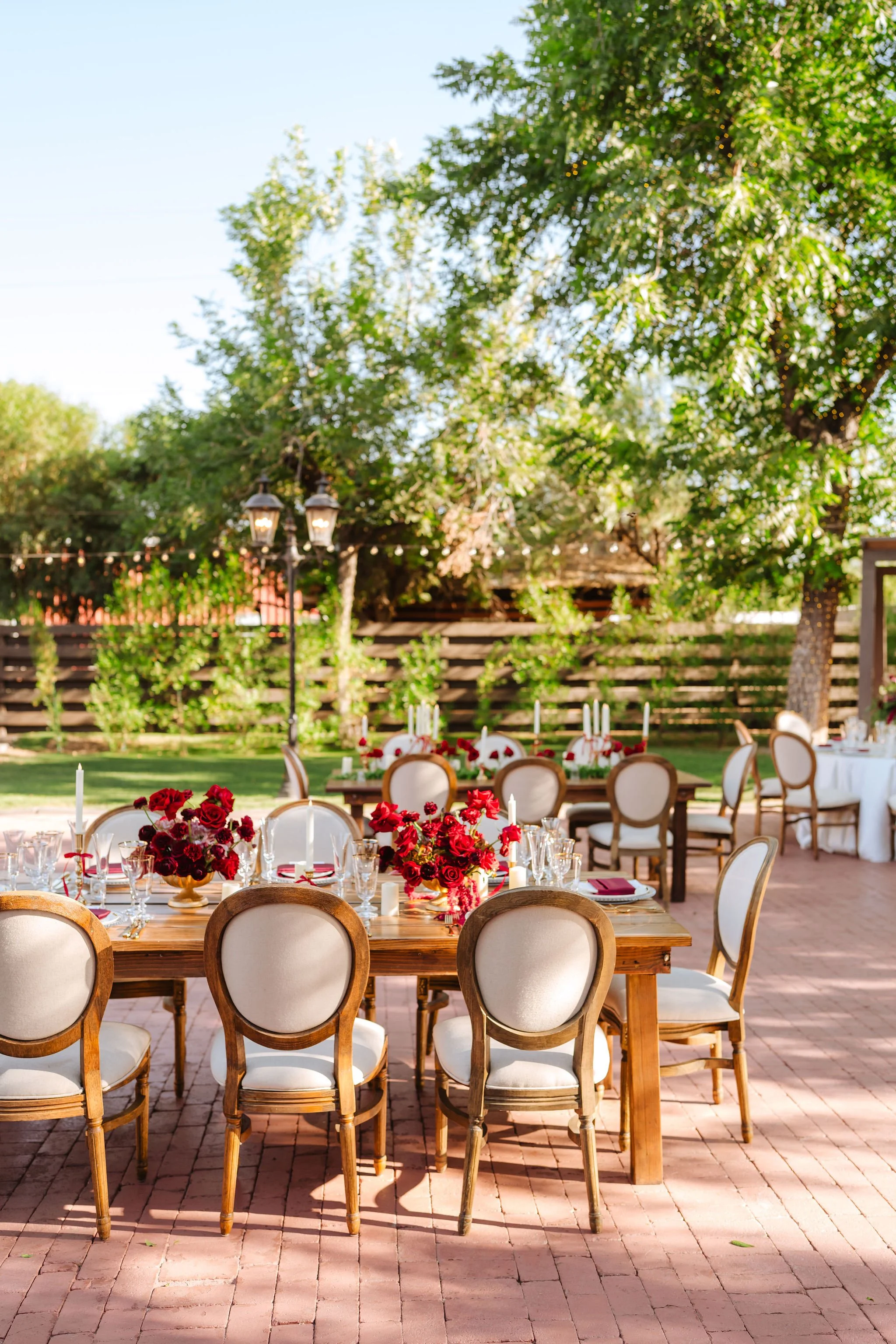 Elegant outdoor wedding reception at Venue at the Grove with red floral accents and garden-inspired tables.