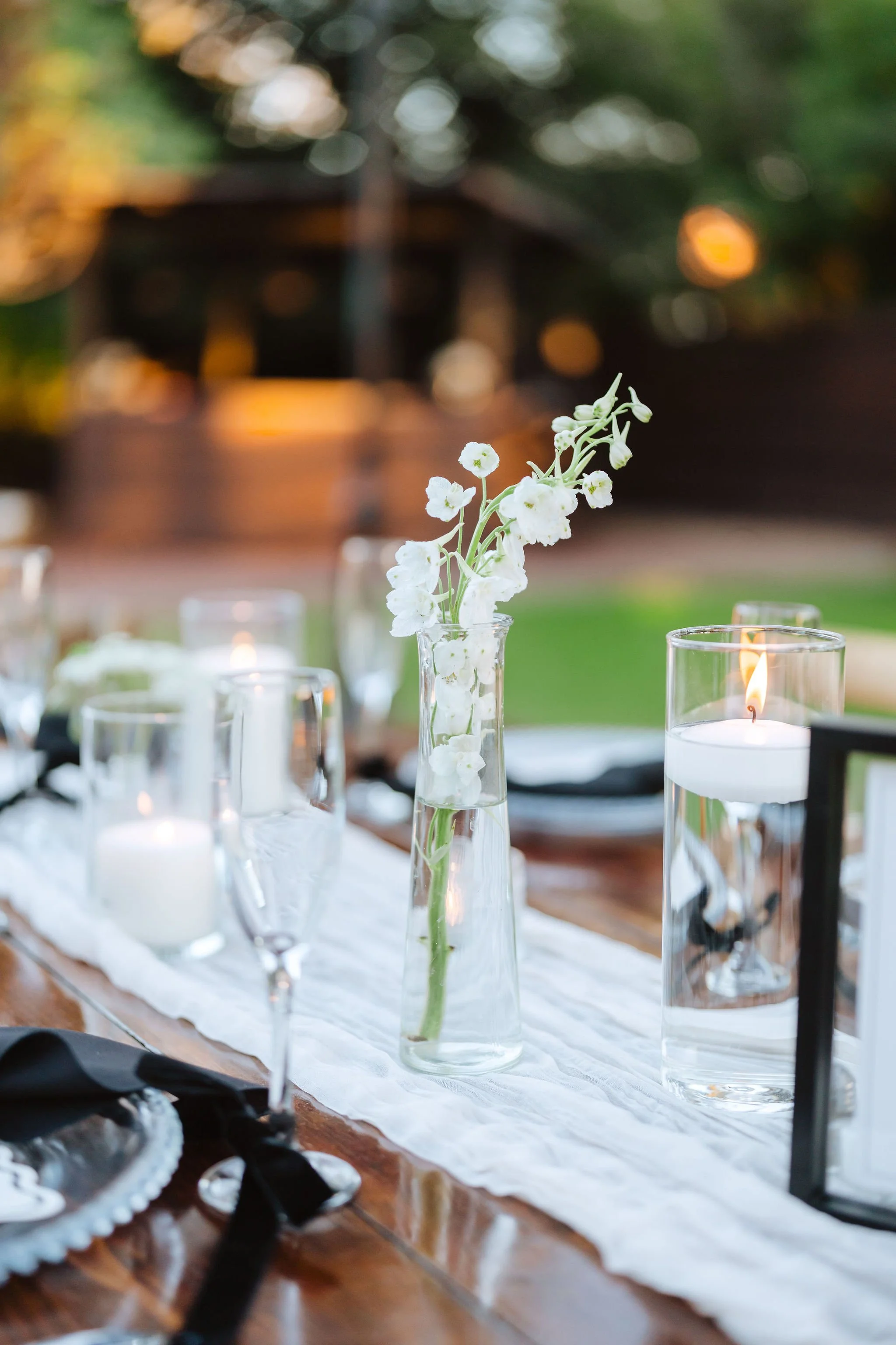 Elegant wedding reception table with white floral details, greenery and candlelight.