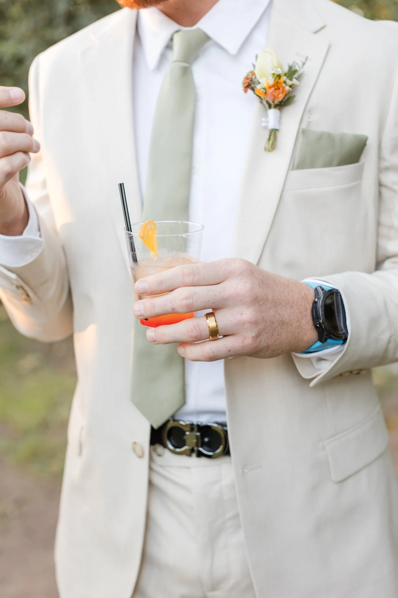 Groom boutonniere featuring a small peach flower and greenery for a romantic fall wedding.