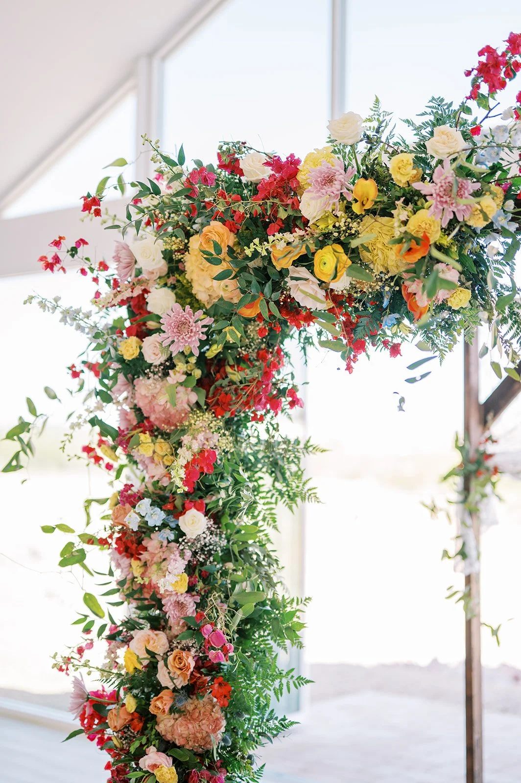 Colorful garden-style wedding floral installation filled with pink, yellow, red, and textural blooms.