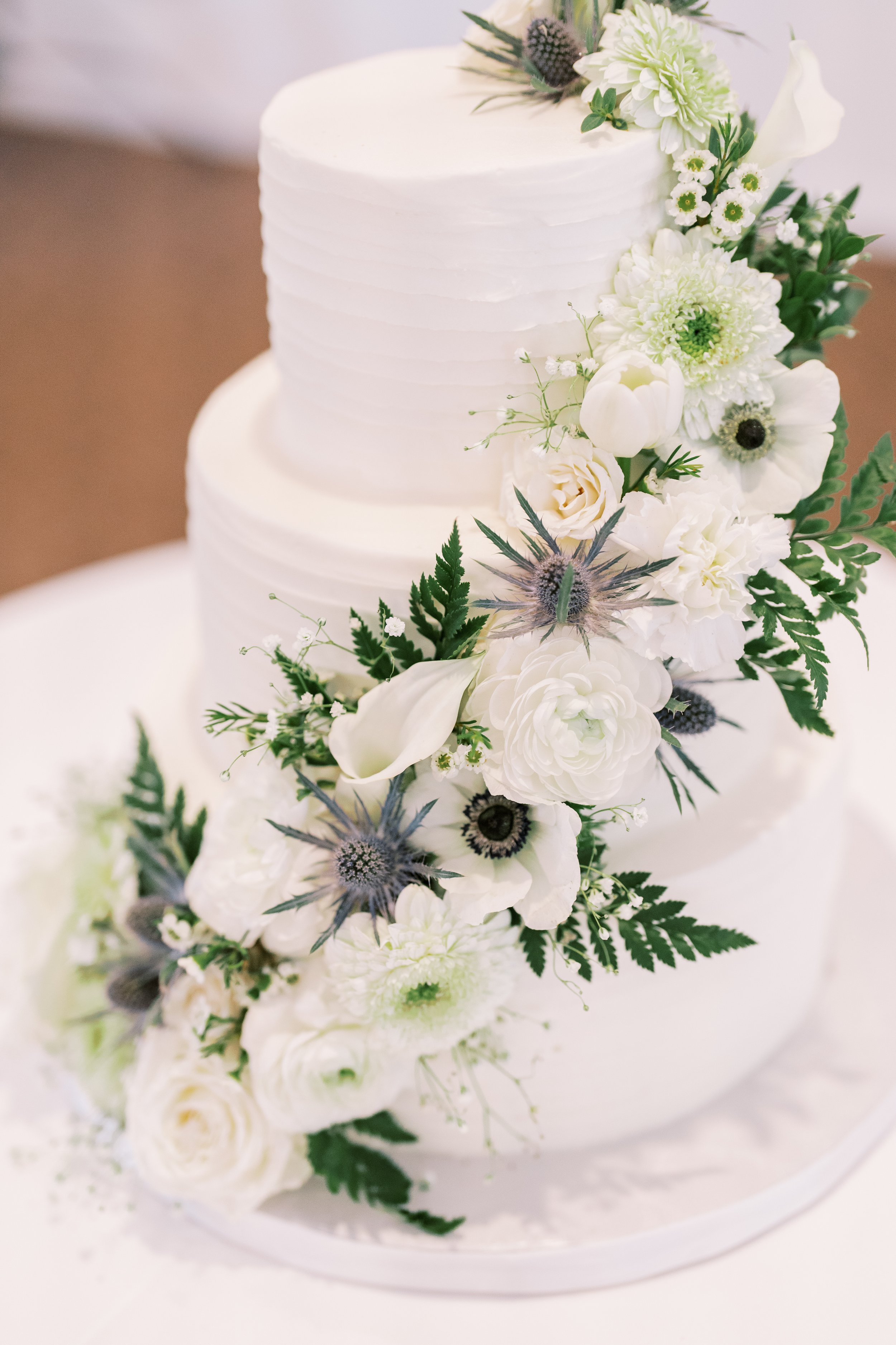 Elegant white wedding flowers with soft blue accents and greenery arranged as a romantic floral detail.