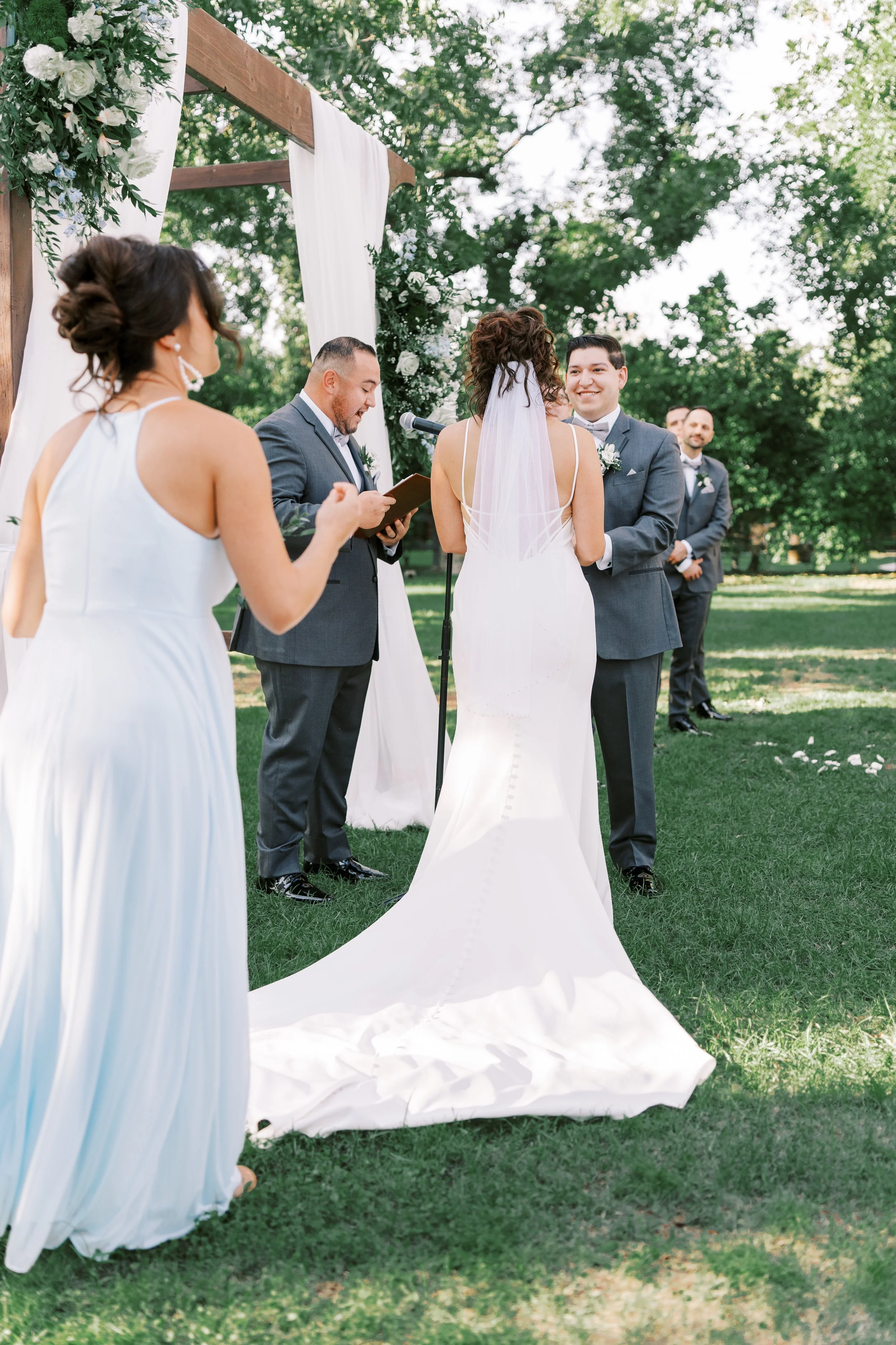 Bride greeting a bridesmaid in a soft blue dress during an outdoor Venue at the Grove wedding.