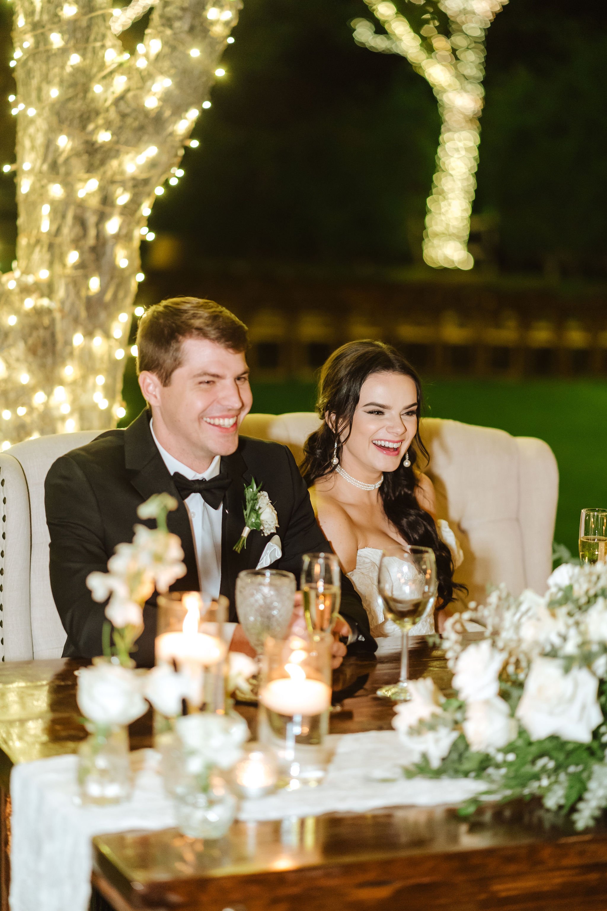 Sierra and Alex at their romantic candlelit wedding reception with white floral centerpieces.