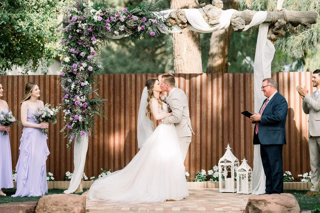 Bride beside a lush purple, blush and white ceremony floral installation at Knotty Barn.