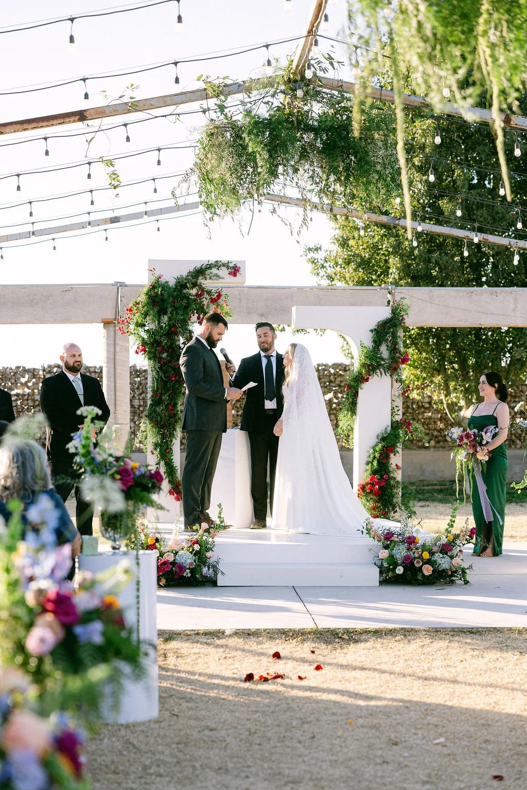 Bride holding a whimsical pink and purple bridal bouquet at a colorful Arizona backyard wedding.