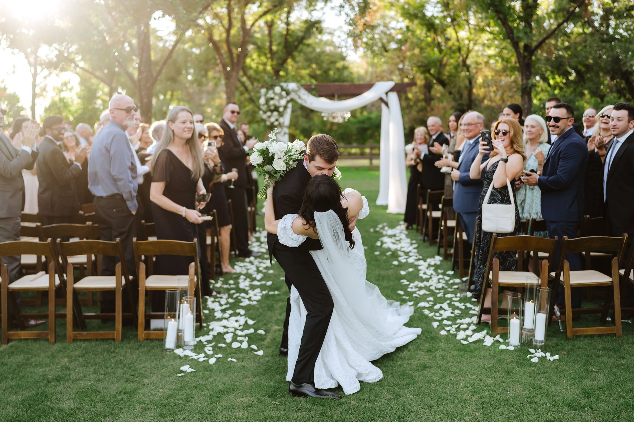 Bride and groom walking down a flower-lined outdoor wedding aisle after their Venue at the Grove ceremony.
