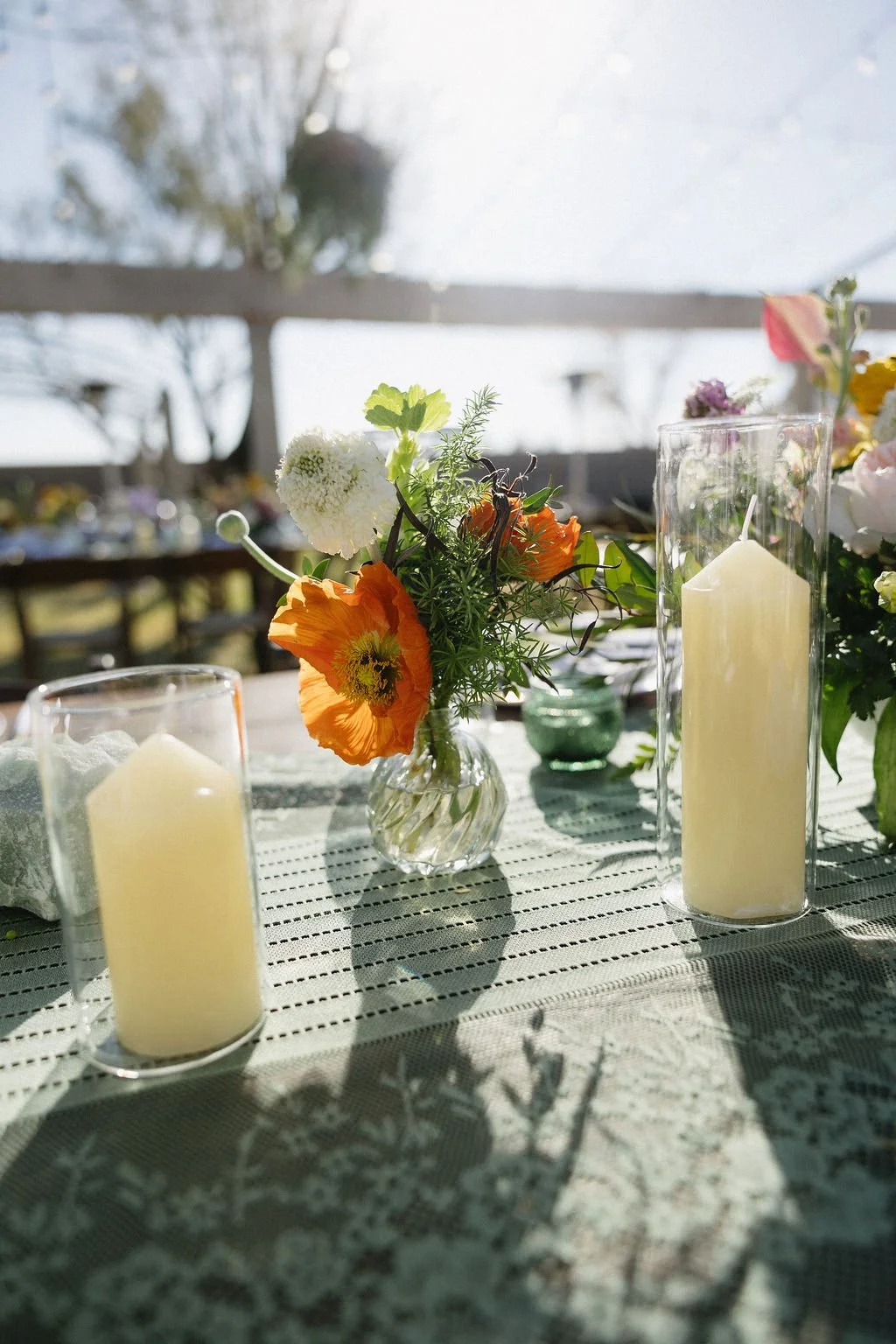 Colorful wedding reception centerpiece with yellow, pink, purple and peach flowers glowing in warm candlelight.
