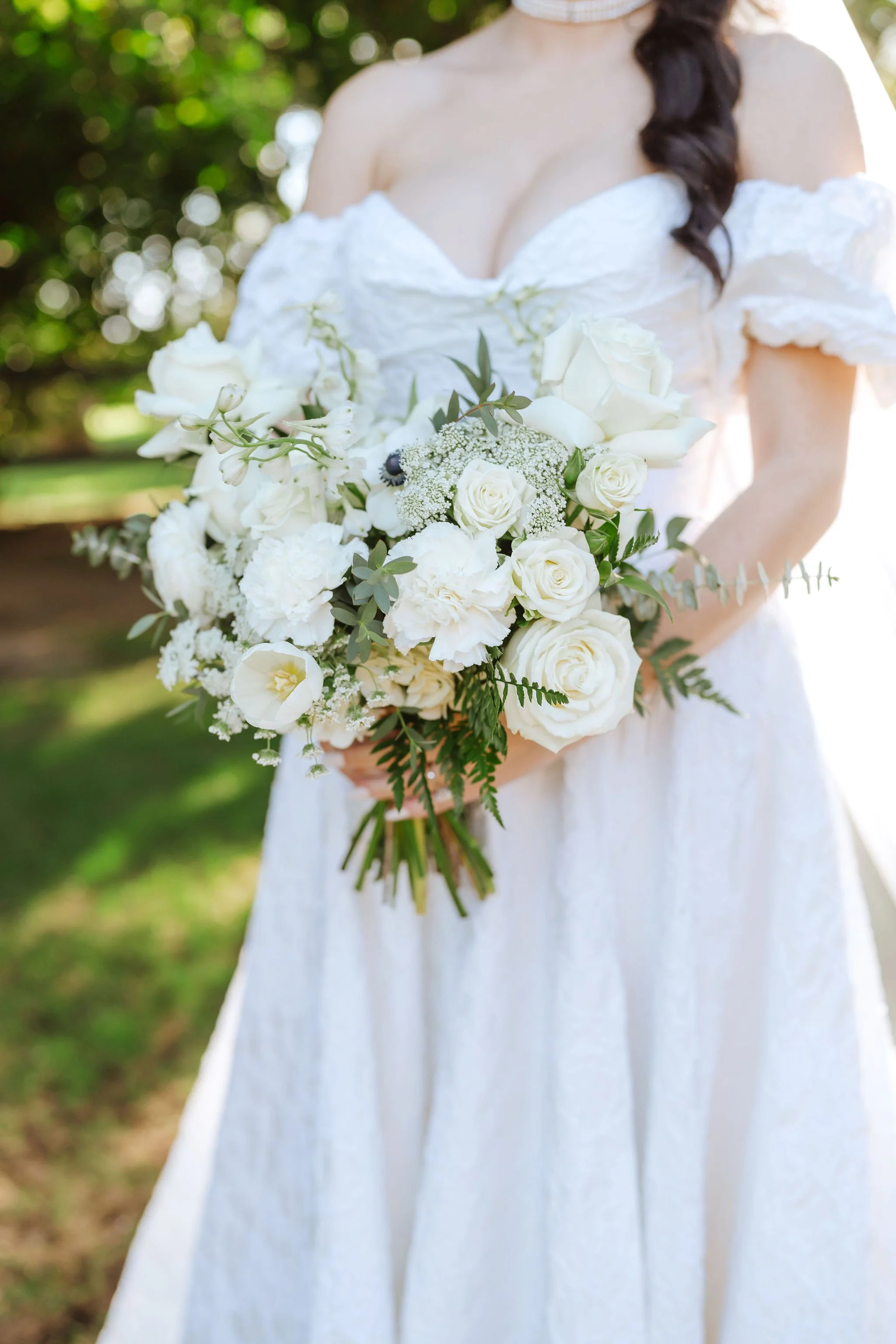 Classic white bridal bouquet featuring white roses, airy blooms and cascading greenery.