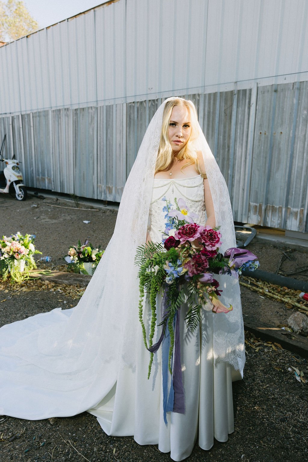 Bride holding a whimsical cascading bouquet with purple, pink and colorful garden-inspired flowers.