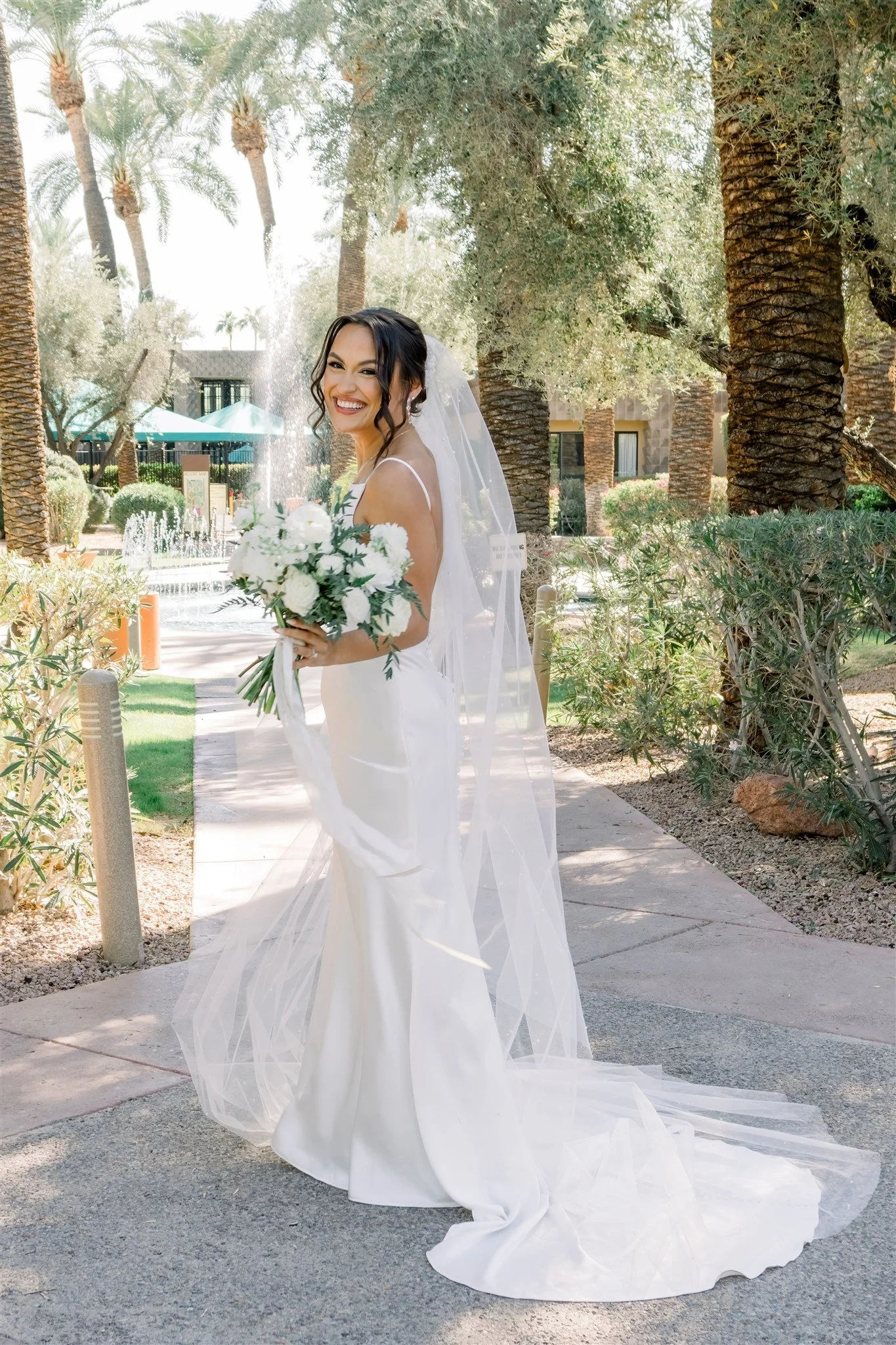 Bride outdoors in Arizona holding a romantic white and green wedding bouquet.