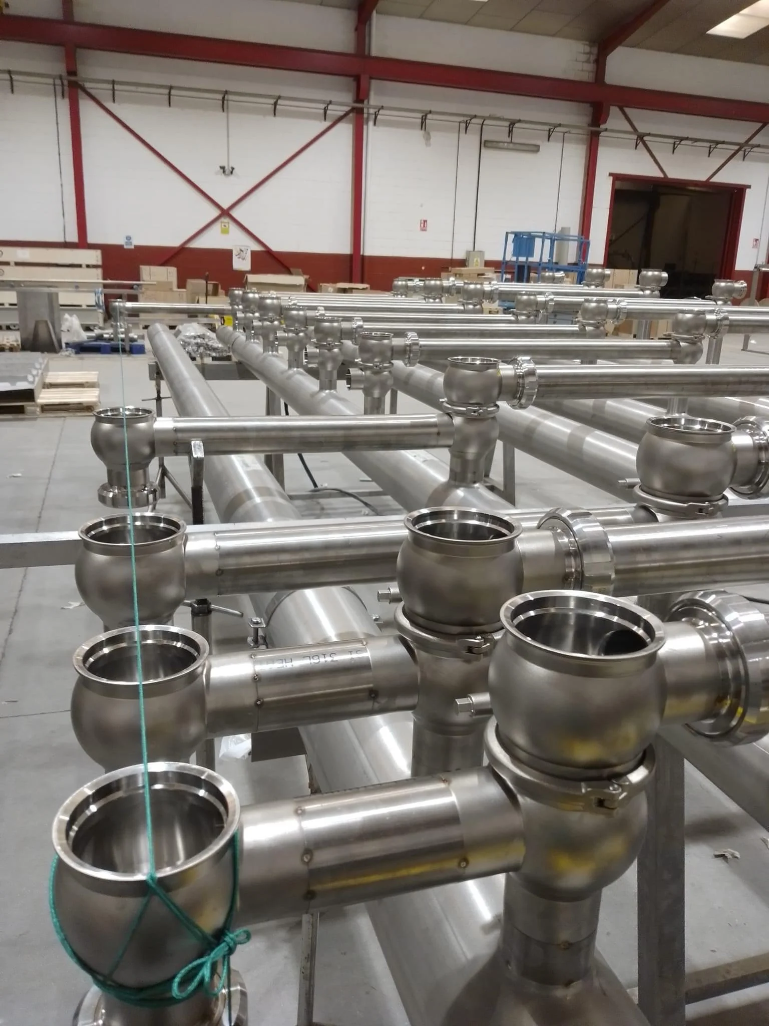 Multiple stainless steel pipes and fittings arranged in a factory or industrial setting.