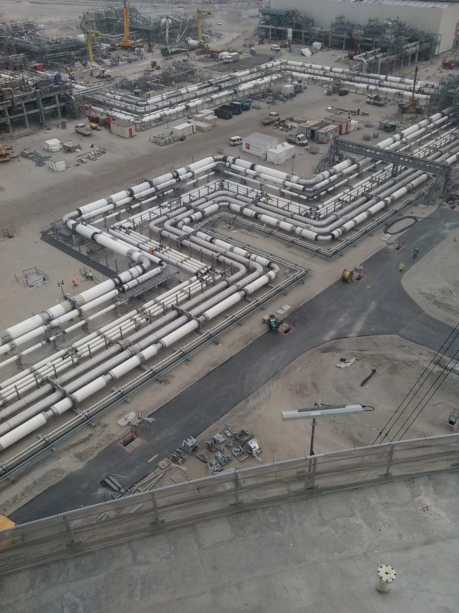 A construction site with extensive piping systems, machinery, and equipment for infrastructure or industrial development, seen from an elevated perspective.