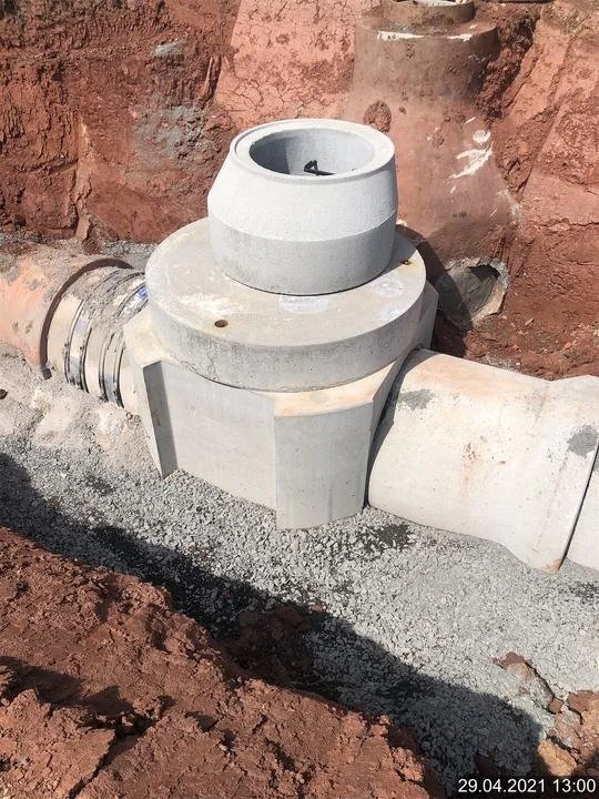 Installation eines Wasserrohrsystems im Boden, bestehend aus großen Betonzylindern und Rohrleitungen, im Boden eingebettet.