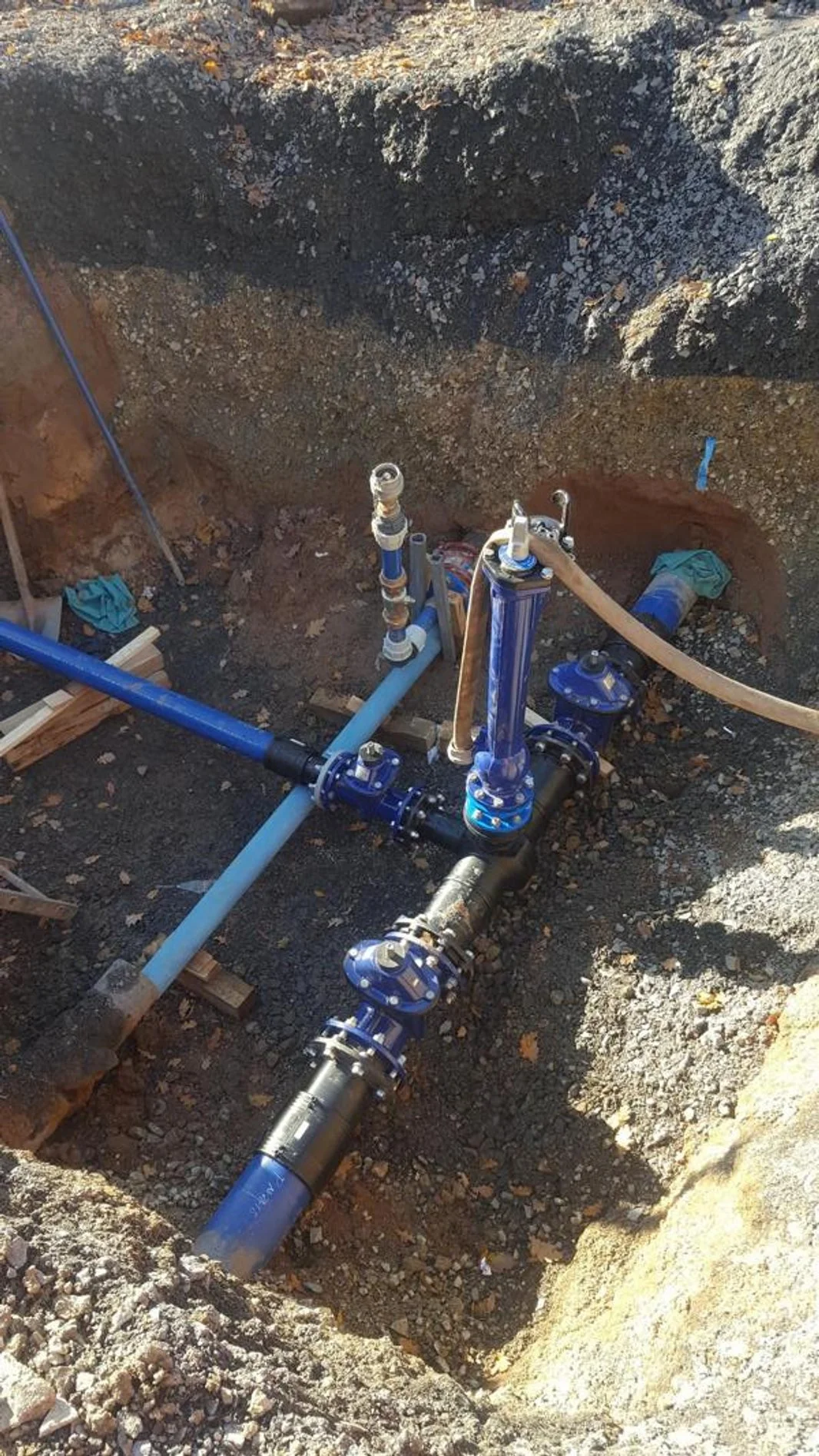 Bodenanalyse im Baugrube mit blauen Rohrleitungen und Armaturen für Wasser- oder Gasversorgung.