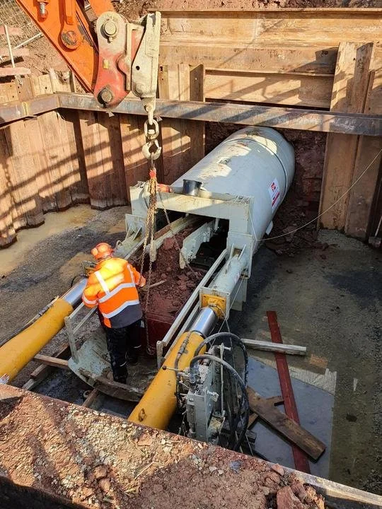 Bauarbeiter mit Hilfe einer Maschine bei Erdarbeiten in einer Baugrube.