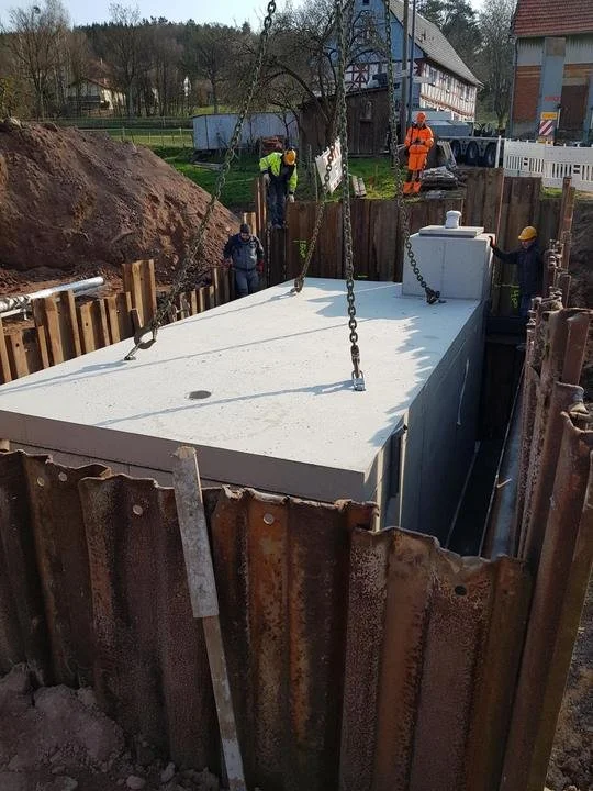 Betonfundament wird auf einer Baustelle installiert, umgeben von Baunägel und Bauarbeitern, die auf das Projekt arbeiten.