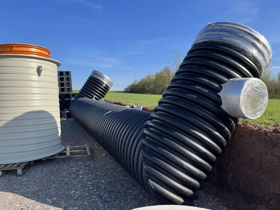 Große schwarze und weiße Kunststoffrohre und Tanks auf einer Baustelle im Freien.