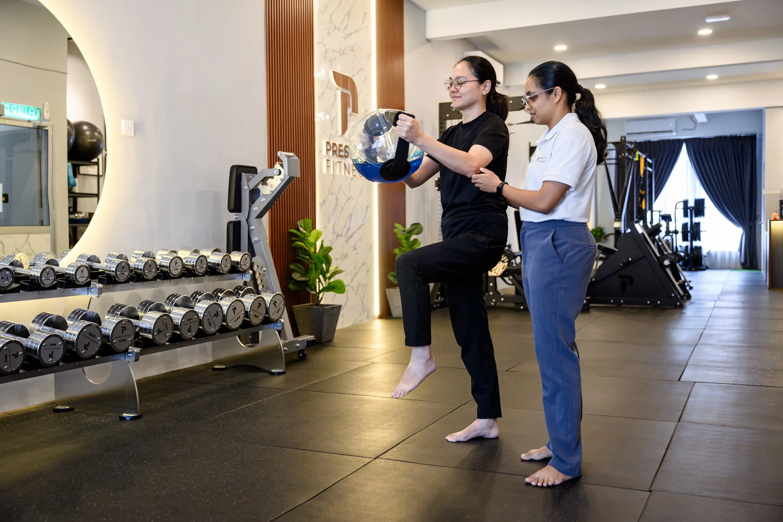 Priya, fitness professional in Ipoh guide middle aged individual to exercise at Prestige Fitness