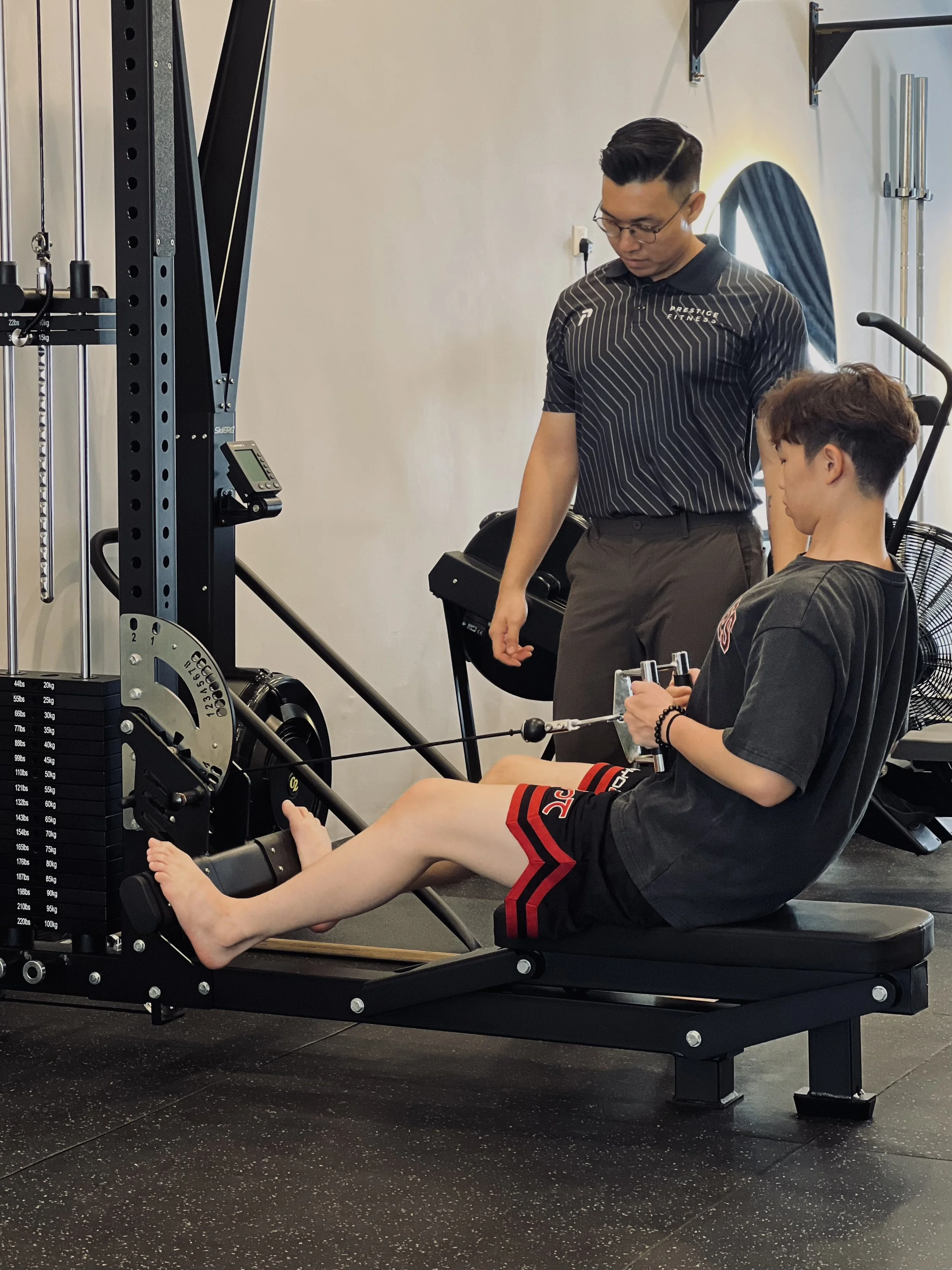 An expert personal trainer in Ipoh is coaching a man to perform row at Prestige Fitness Personal Training, best personal training gym in Ipoh