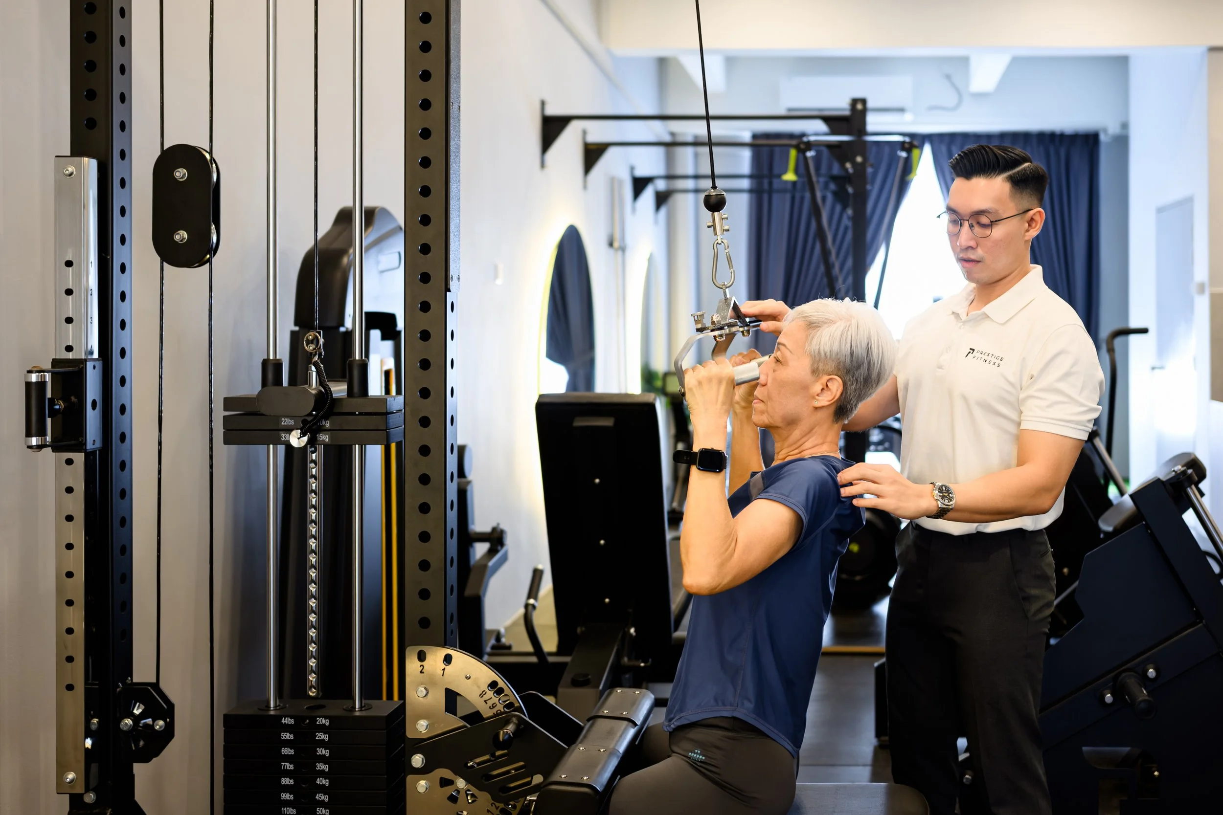 The Best Personal trainer in Ipoh assisting a client with an exercise using a stability ball in Prestige Fitness